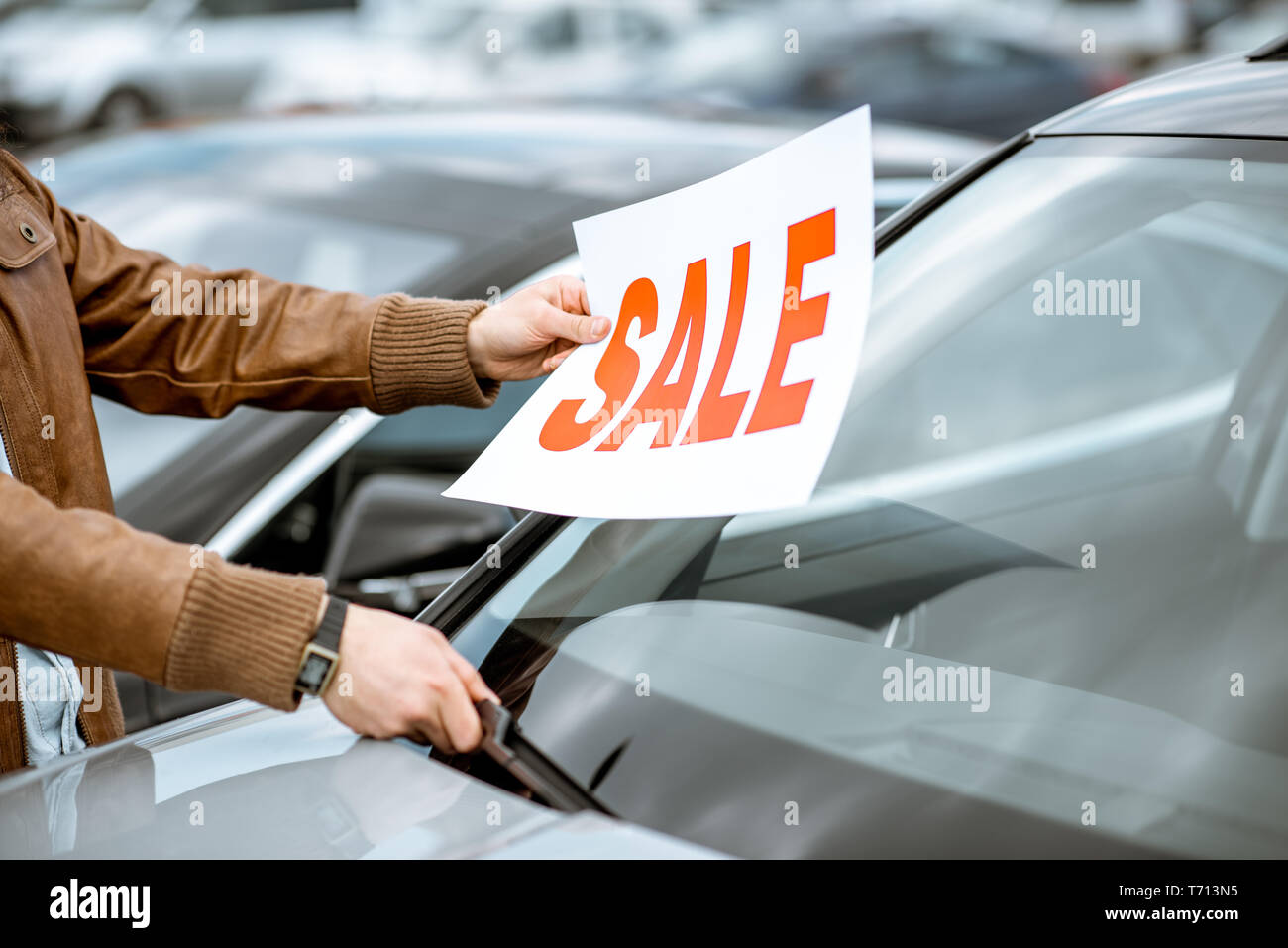Vendedor poniendo venta placa en el coche parabrisas en el terreno abierto  de un concesionario, Vista cercana Fotografía de stock - Alamy