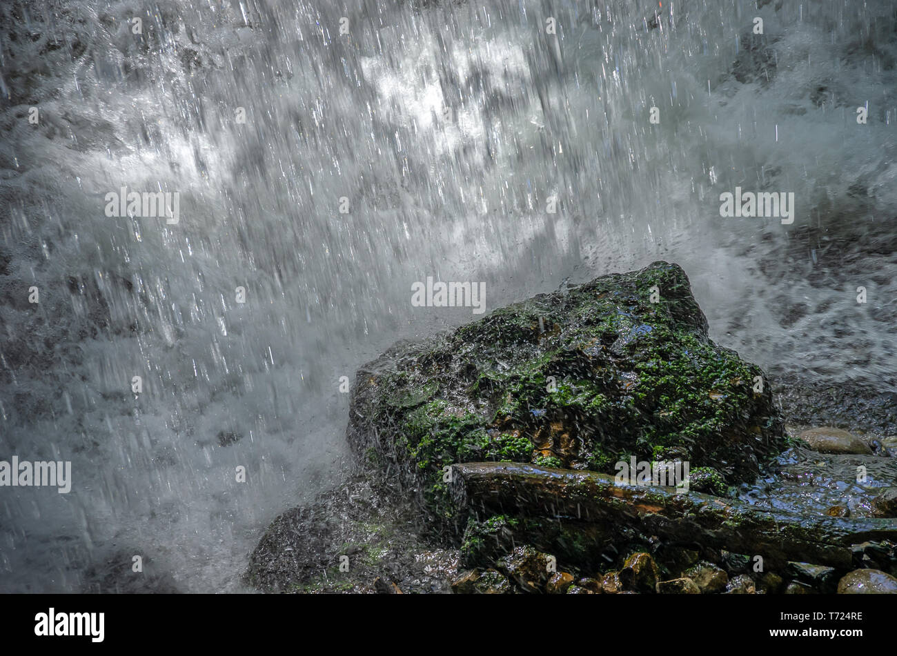 El agua está cayendo en una piedra de musgo verde. Foto de stock