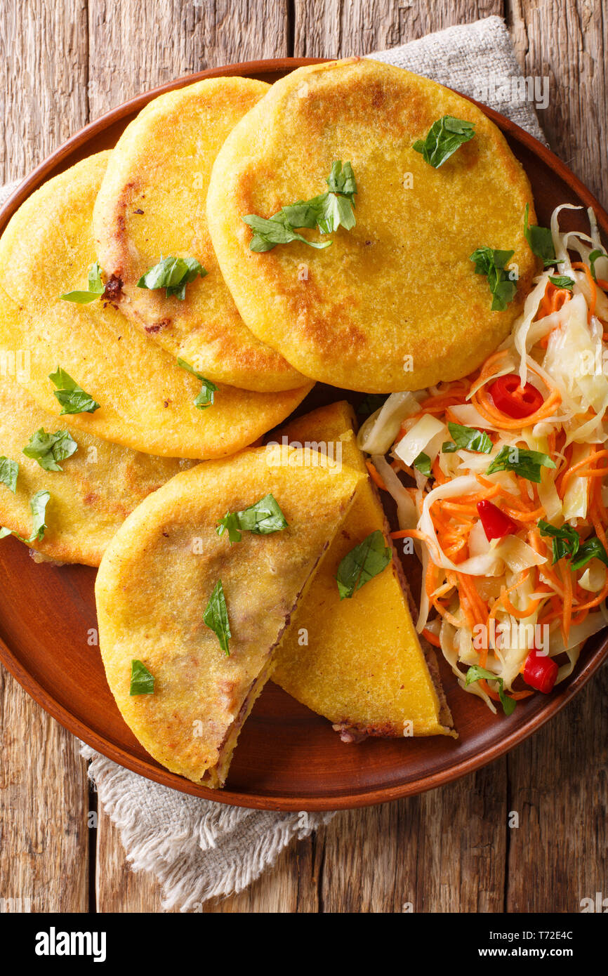Pupusas tradicionales latinoamericanos y servido con closeup curtido en una placa sobre la mesa. Vista superior de la vertical desde arriba Foto de stock