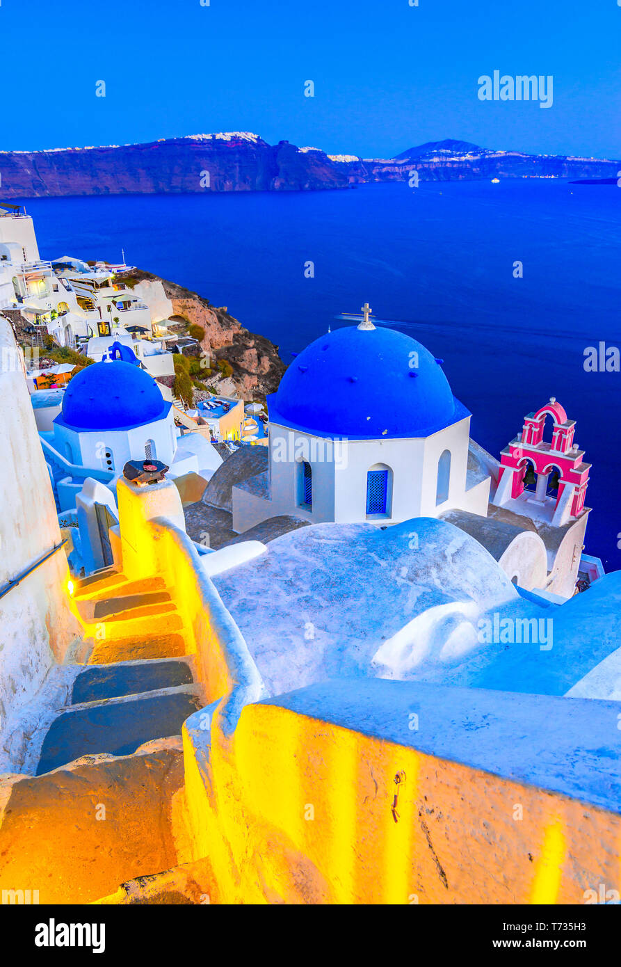 Oia, isla de Santorini, Grecia al atardecer. Famosos y tradicionales casas blancas e iglesias con cúpulas azules a lo largo de la Caldera, el mar Egeo. Foto de stock