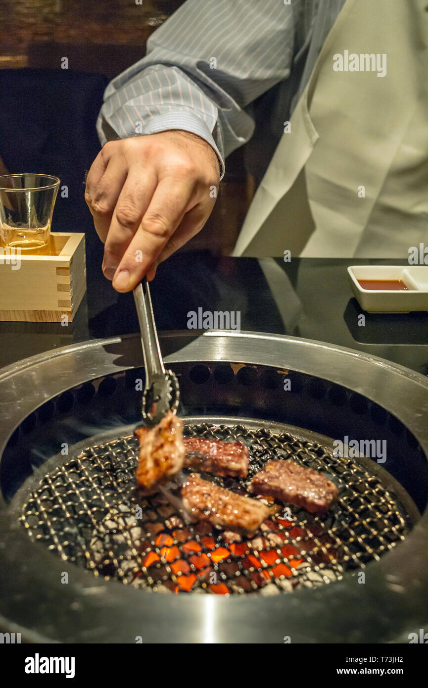 Hombre cocinando piezas de carne en una parrilla de mesa en un restaurante  de barbacoa coreano, Tokio, Japón Fotografía de stock - Alamy