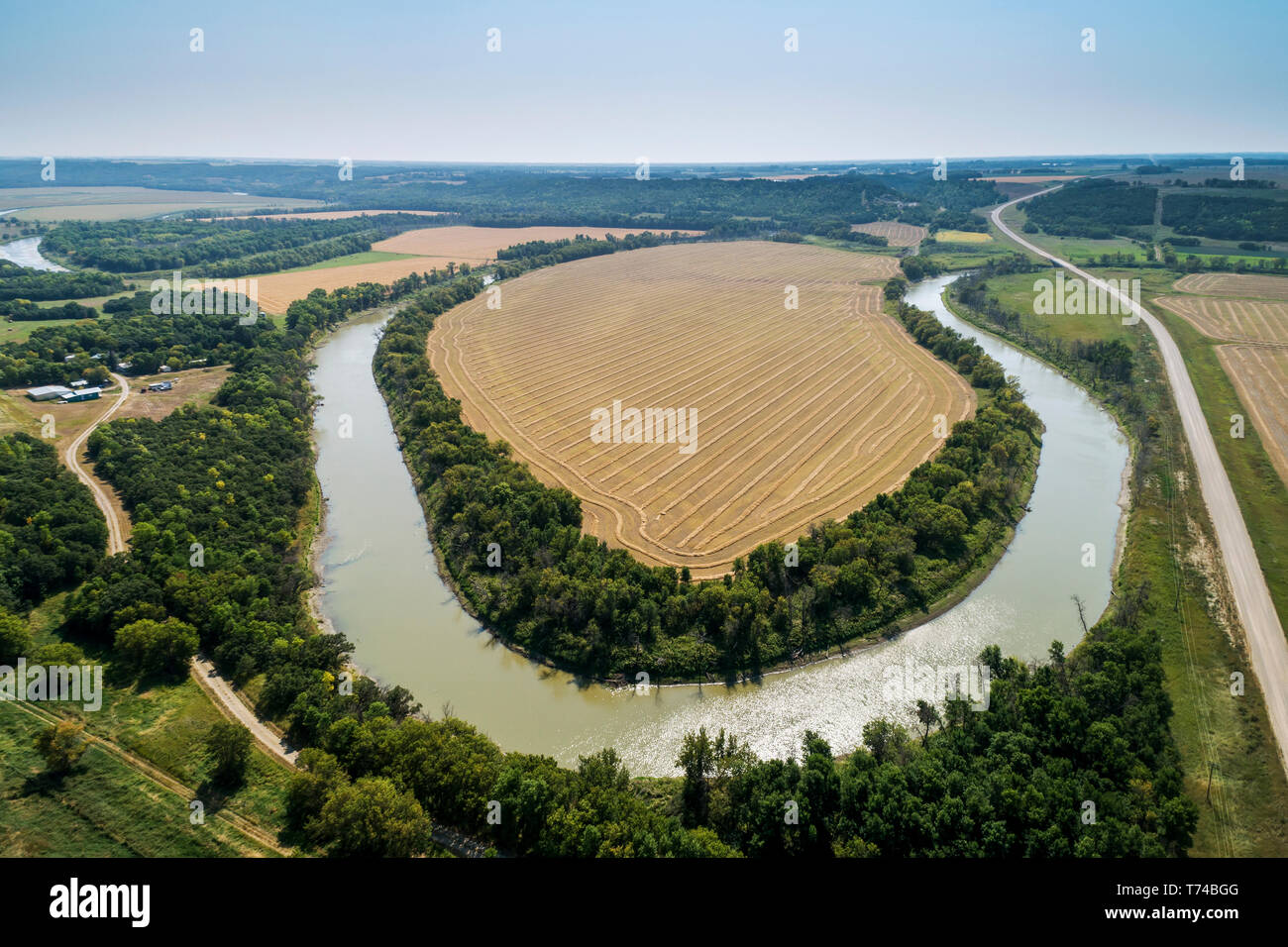 Vista aérea de una curva de 270 grados en un río con un corte de grano en la cosecha del campo rodeado por árboles de roble, al norte del Lago; en Manitoba, Canadá Foto de stock