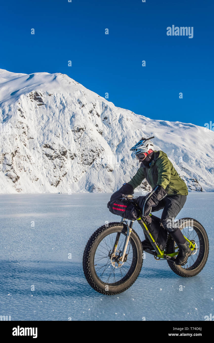 Un hombre montando su fatbike cruzando el lago Portage congelado a mediados de invierno, en el centro-sur de Alaska, Alaska, Estados Unidos de América Foto de stock