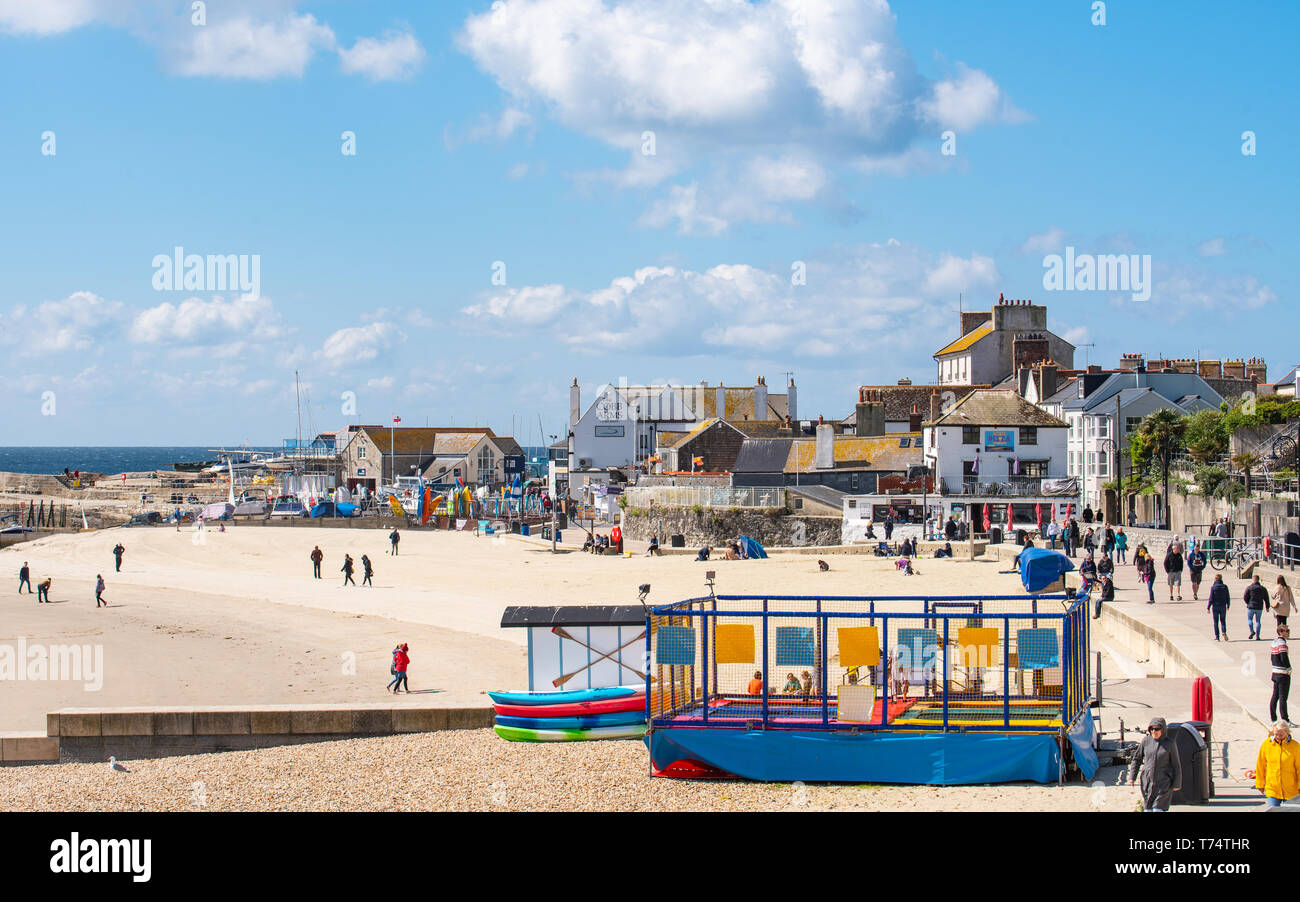 Lyme Regis, Dorset, Reino Unido. 4 de mayo de 2019. El clima del REINO UNIDO: Un brillante y soleado comienza a un frío día festivo en Lyme Regis, ya que las temperaturas caen en picado. Los visitantes valiente la fría brisa para disfrutar de la nitidez de los cielos azules y soleados hechizos en la playa en Lyme Regis a pesar del frío, del viento y agudamente la congelación en condiciones de frío. Aire frío ártico está configurado para traer un frente frío durante la mayor parte del país, en los comienzos de mayo Bank Holiday Weekend. Crédito: Celia McMahon/Alamy Live News Foto de stock