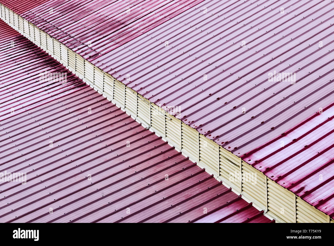 Vista detallada de un techo hecho de hojas de metal de color rojo. Un voladizo diagonal da una impresión tridimensional. Foto de stock
