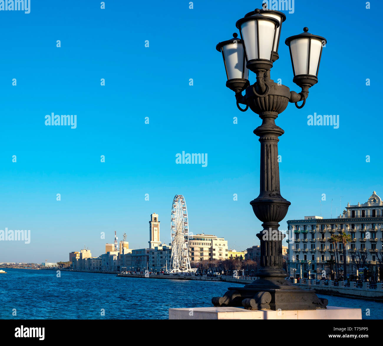 Bari, Italia - 8 de abril de 2018: primer plano característico del poste de la luz y en el fondo la noria montada en el paseo marítimo Foto de stock