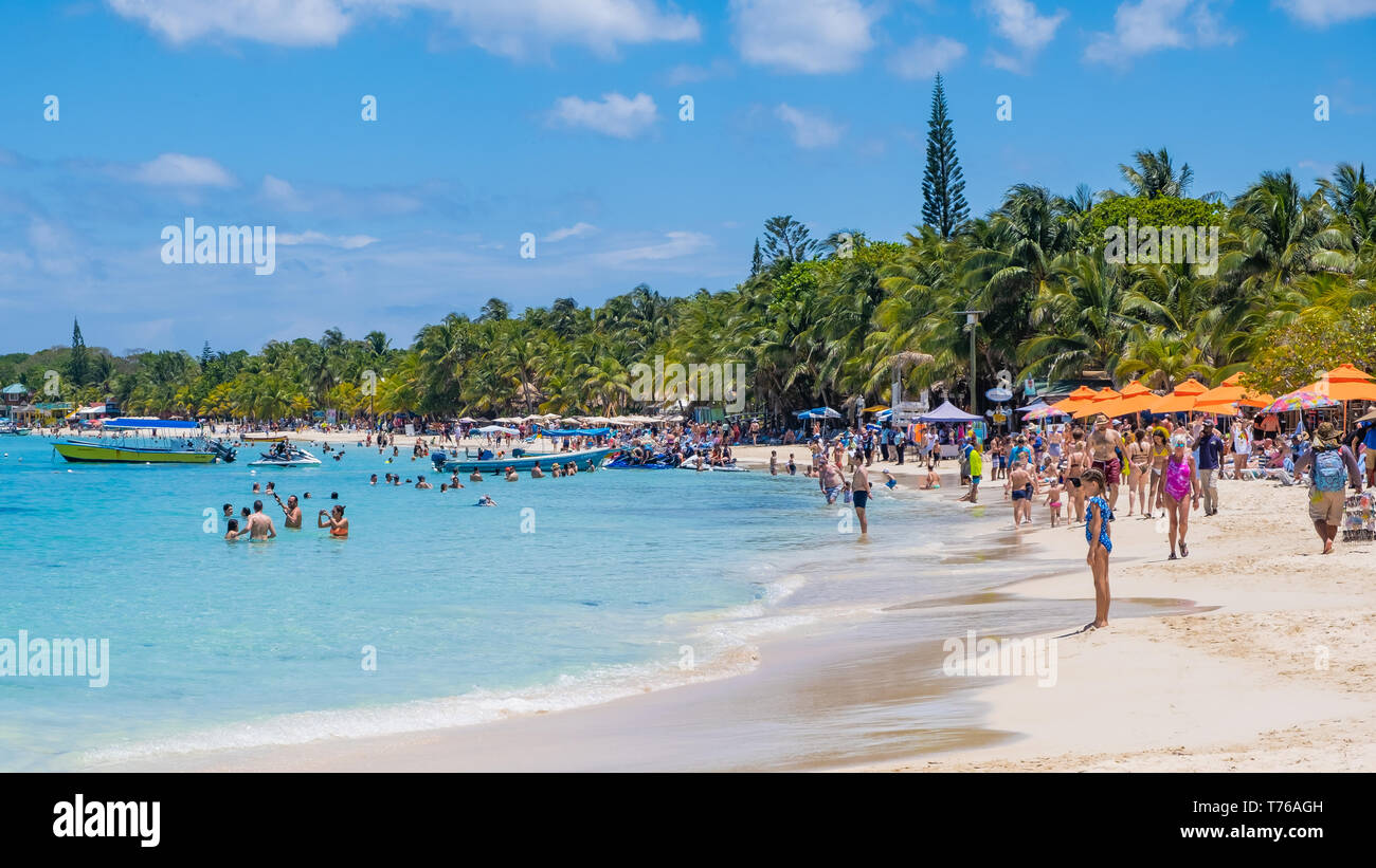 Gente disfrutando de la playa de West Bay en Roatán, Honduras en un soleado día de abril. Foto de stock