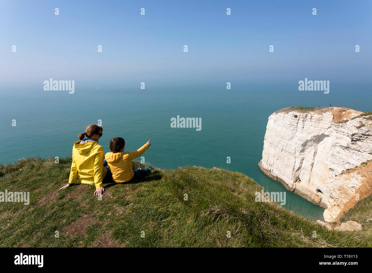 Francia, Normandía: Madre e hijo sentado sobre el césped cubierto de roca acantilados por encima del arco de Playa Etretat Foto de stock