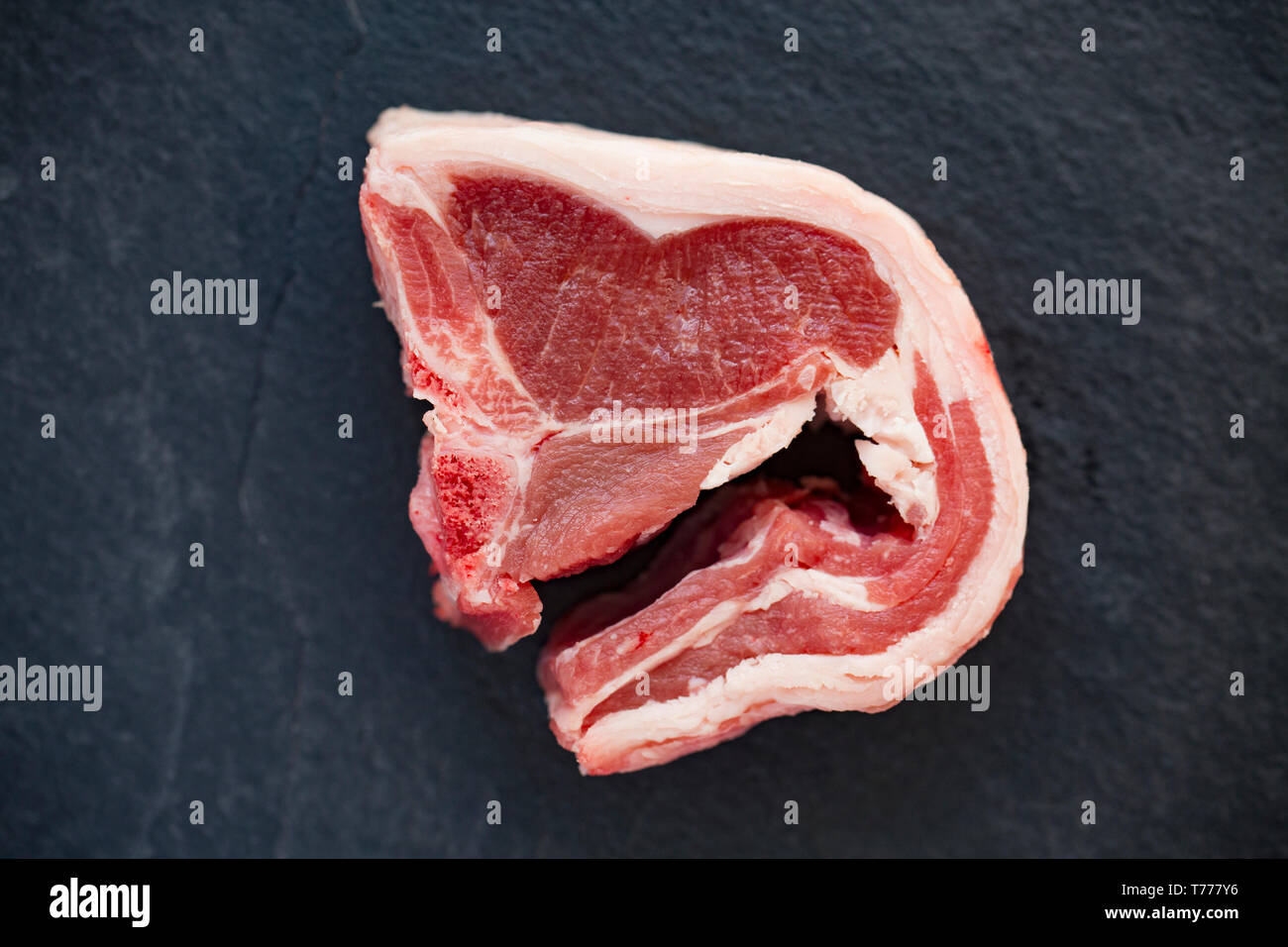 Una sola, crudos y sin cocer British lamb chop compradas en un supermercado en el Reino Unido y se muestran en un fondo de pizarra. Dorset, Inglaterra GB Foto de stock