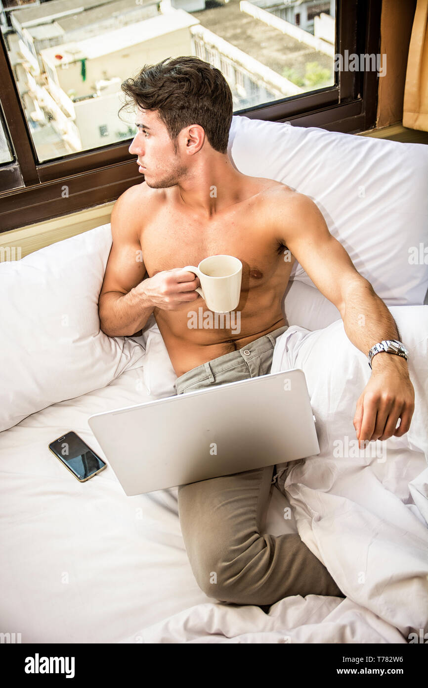 Hombre joven desnudo en la cama con taza de café o té Fotografía de stock -  Alamy