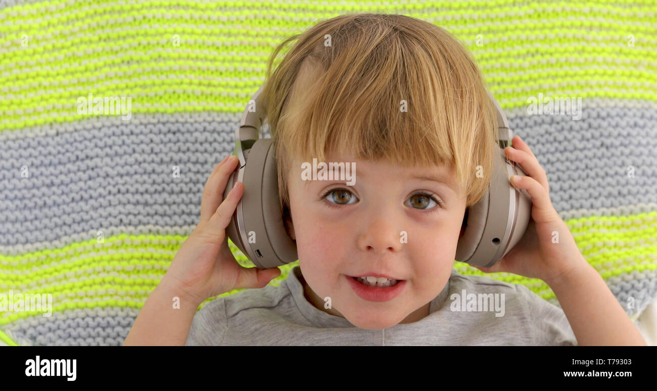El Bebé Lindo Con Los Auriculares Escucha La Música En Casa Imagen