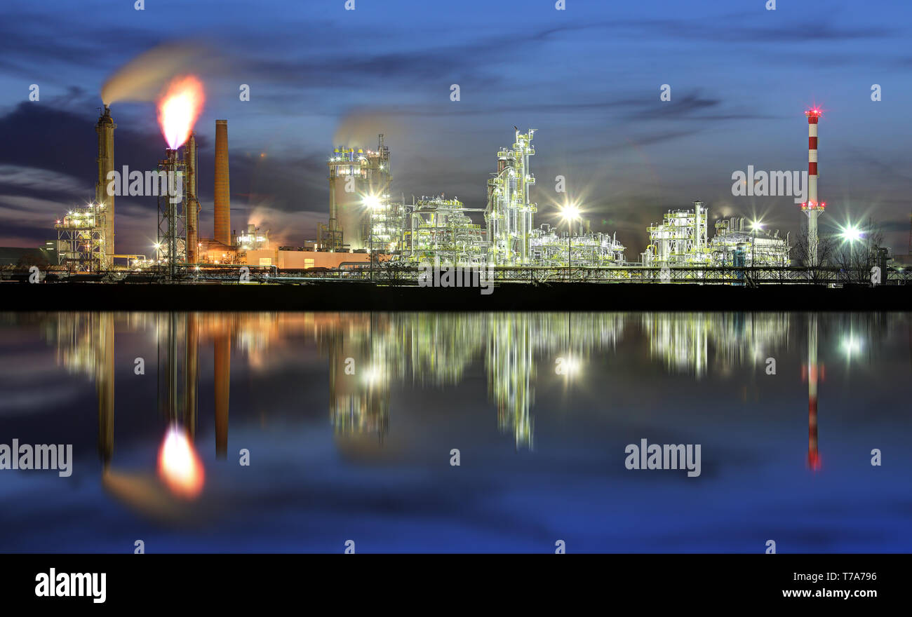 Refinería de petróleo en la noche con el reflejo en el agua Foto de stock