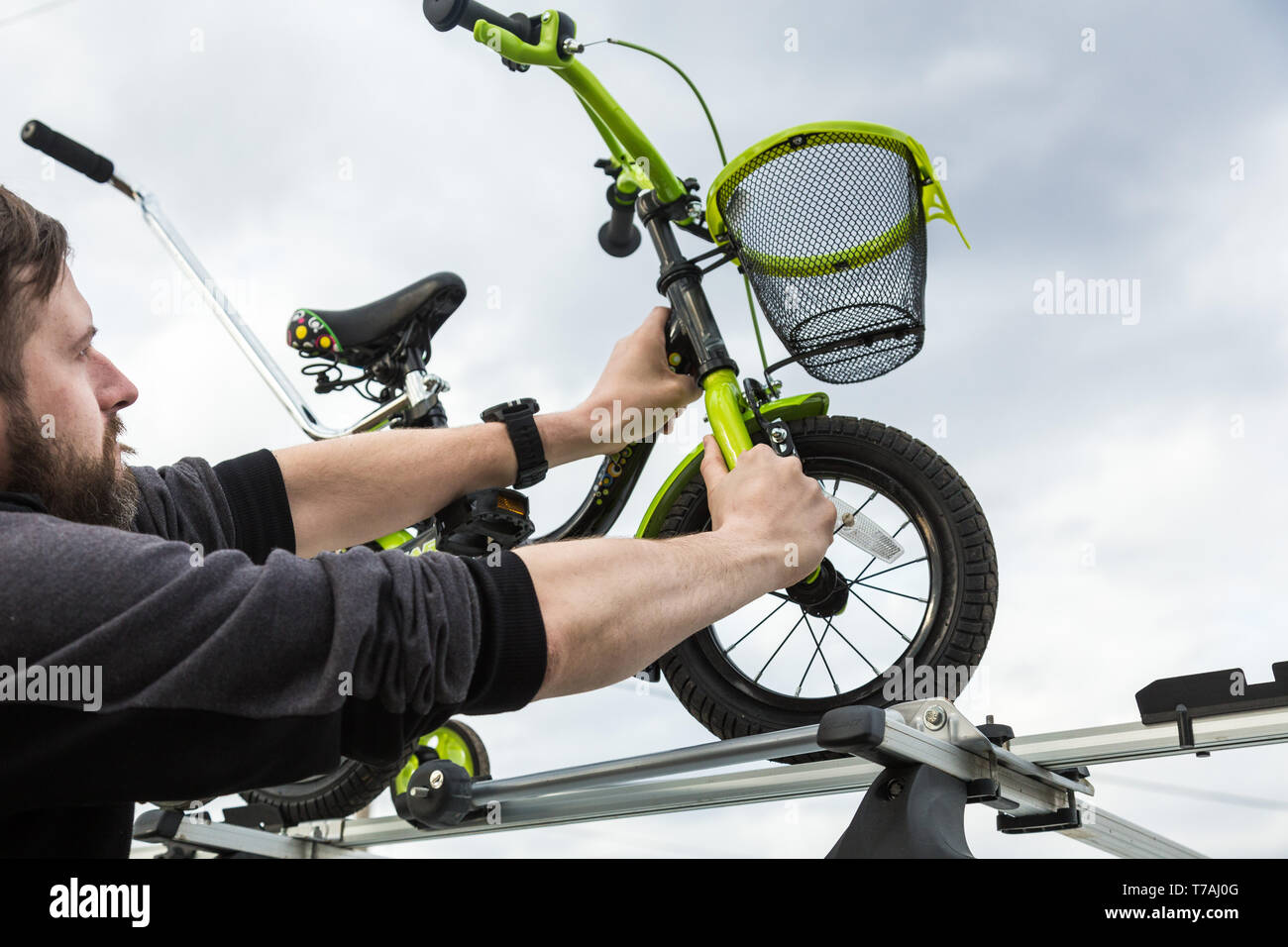 El transporte de la bicicleta - un hombre fija e instala una bicicleta  infantil sobre el techo de un coche en un montaje especial para el  transporte de bicicletas. La decisión t