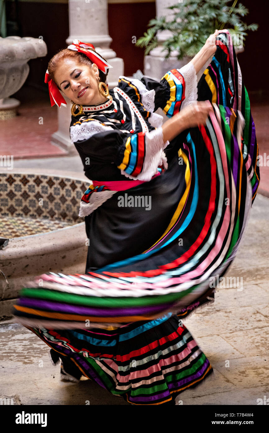 Un bailarín folclórico mexicano en un tradicional vestido de china poblana  realiza el Jarabe de danza folclórica en el patio de estilo arcade del  Ayuntamiento de Jalostotitlan, Jalisco, México Fotografía de stock -