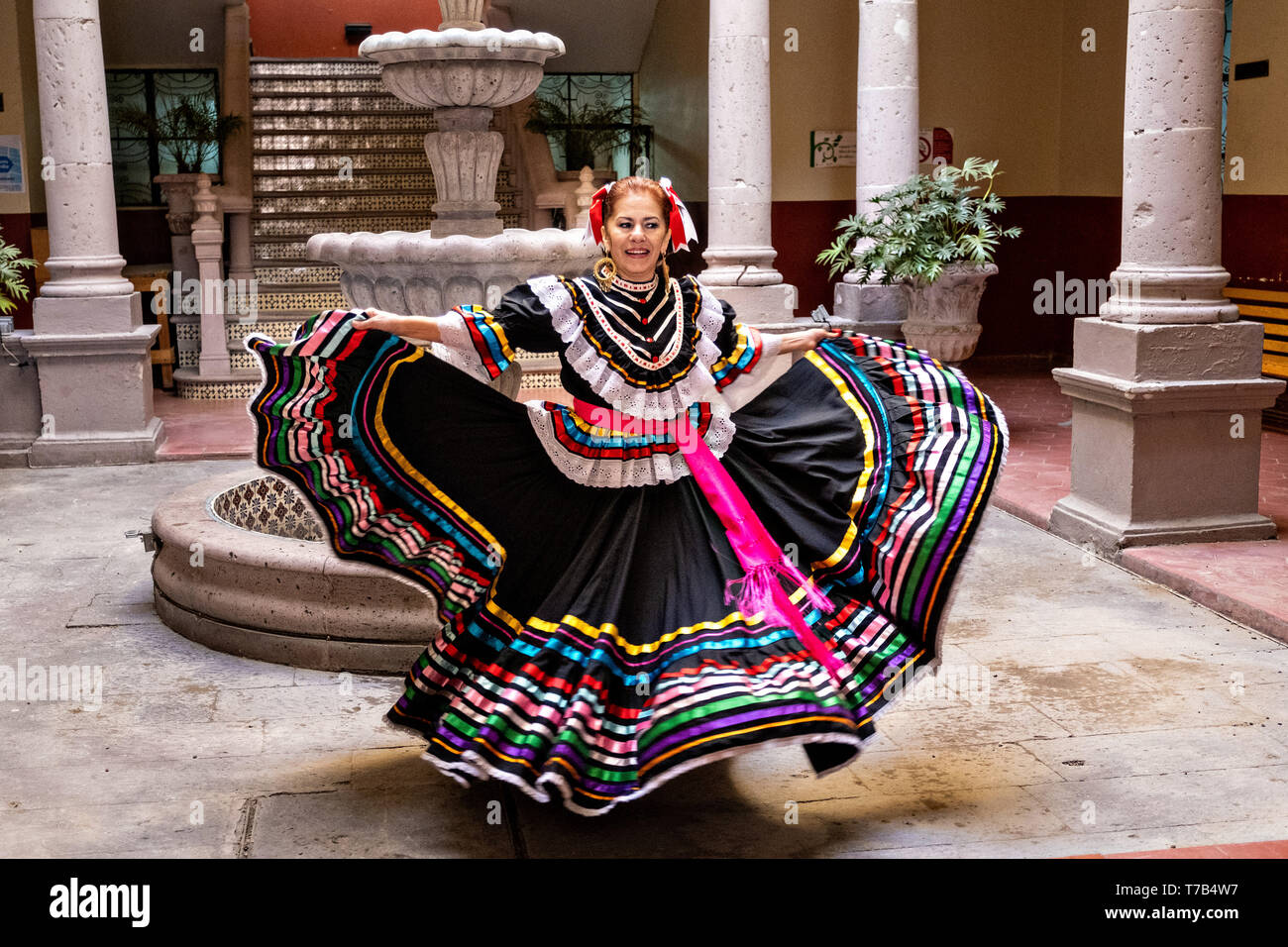 Un bailarín folclórico mexicano en un tradicional vestido de china poblana  realiza el Jarabe de danza folclórica en el patio de estilo arcade del  Ayuntamiento de Jalostotitlan, Jalisco, México Fotografía de stock -