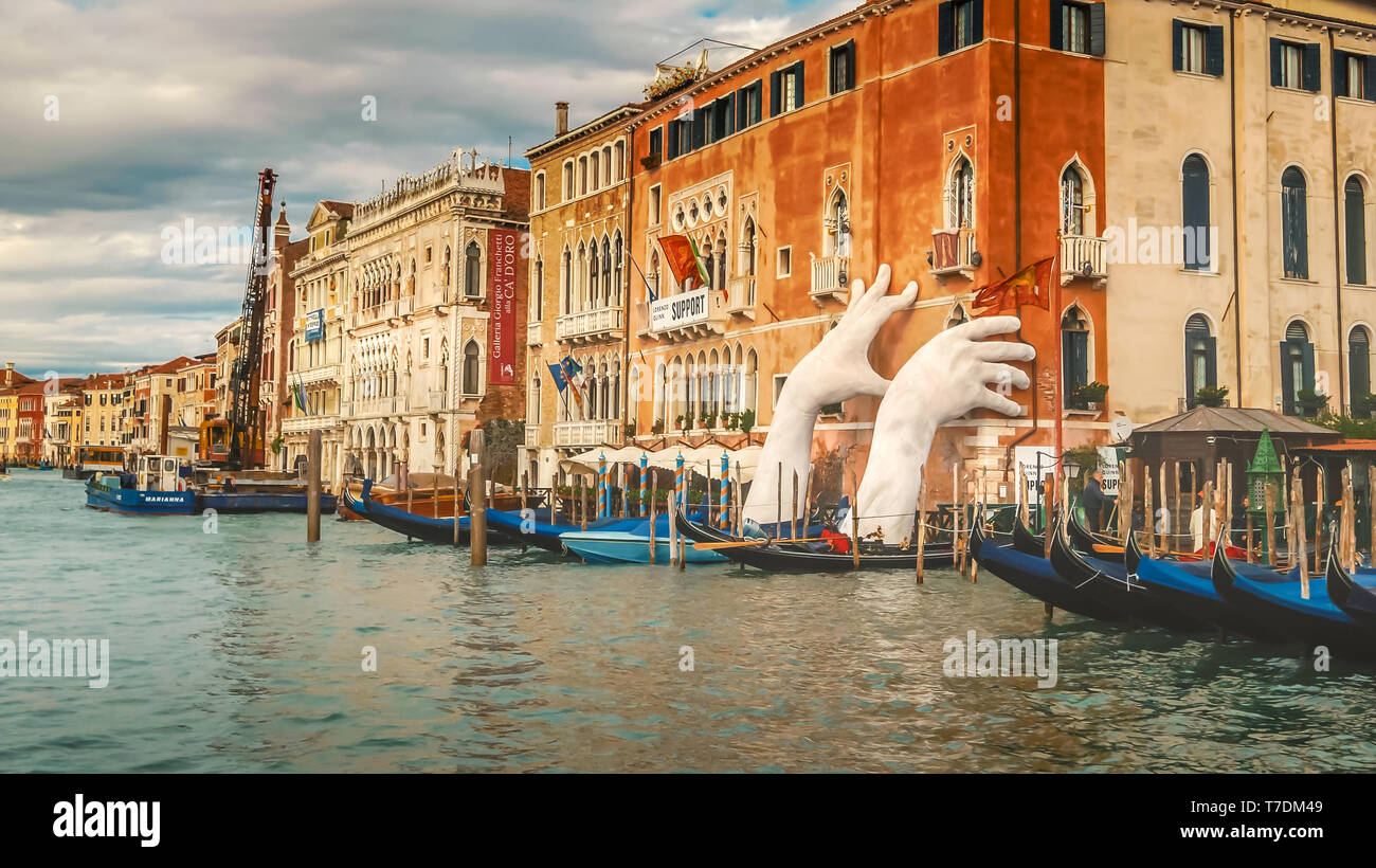 Las manos gigantescas esculturas de Lorenzo Quinn parece sostener un edificio, junto al Gran Canal de Venecia, Italia El apoyo muestra preocupación por la effe Foto de stock