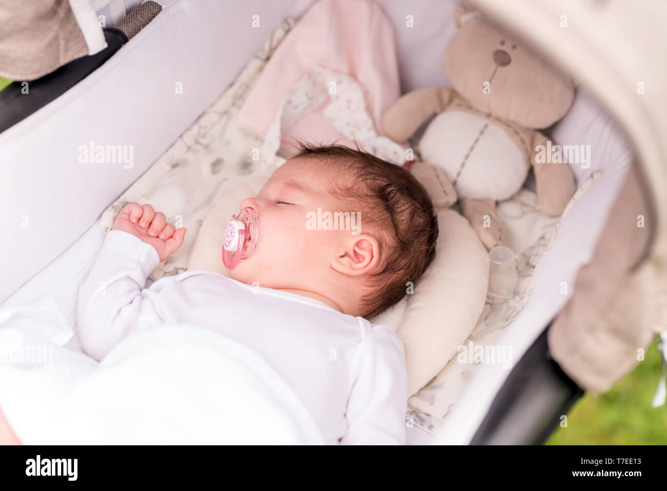 Bebé recién nacido durmiendo en cochecito blanco en una caminata en el parque de verano. Nueva niño nacido siesta al aire libre en un día soleado Bebé recién nacido durmiendo en cochecito blanco en una caminata en el parque de verano. Nueva niño nacido siesta al aire libre en un día soleado