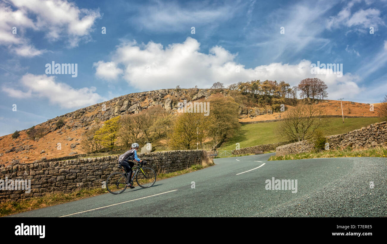 Ciclista femenino andar en bicicleta por la empinada subida de Côte de Barden Moor, parte del Tour de Yorkshire 2019 carrera ciclista ruta, Valles de Yorkshire, Reino Unido Foto de stock