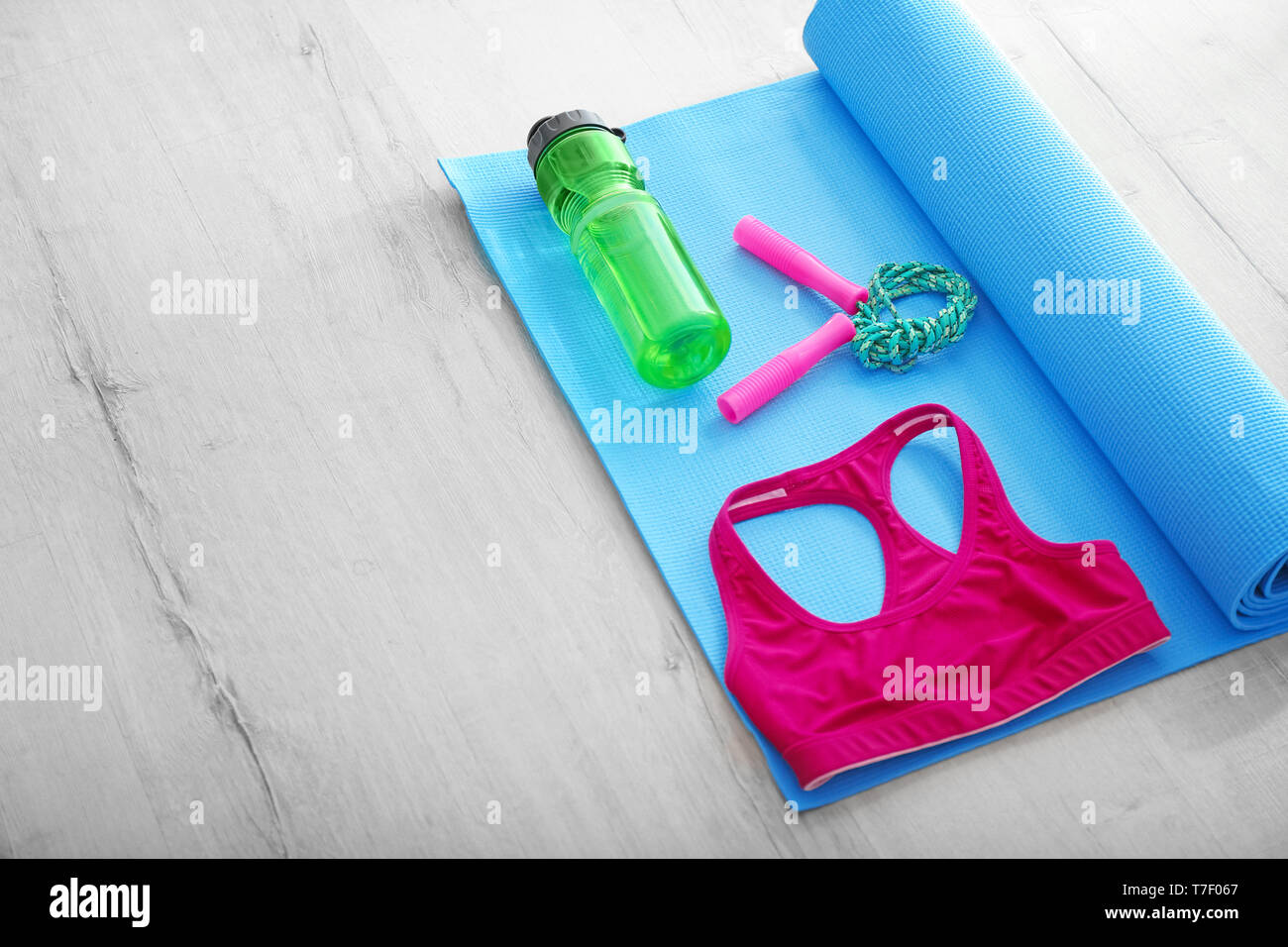 Esterilla de yoga con saltar la cuerda, botella de agua y ropa deportiva  sobre un piso de madera Fotografía de stock - Alamy