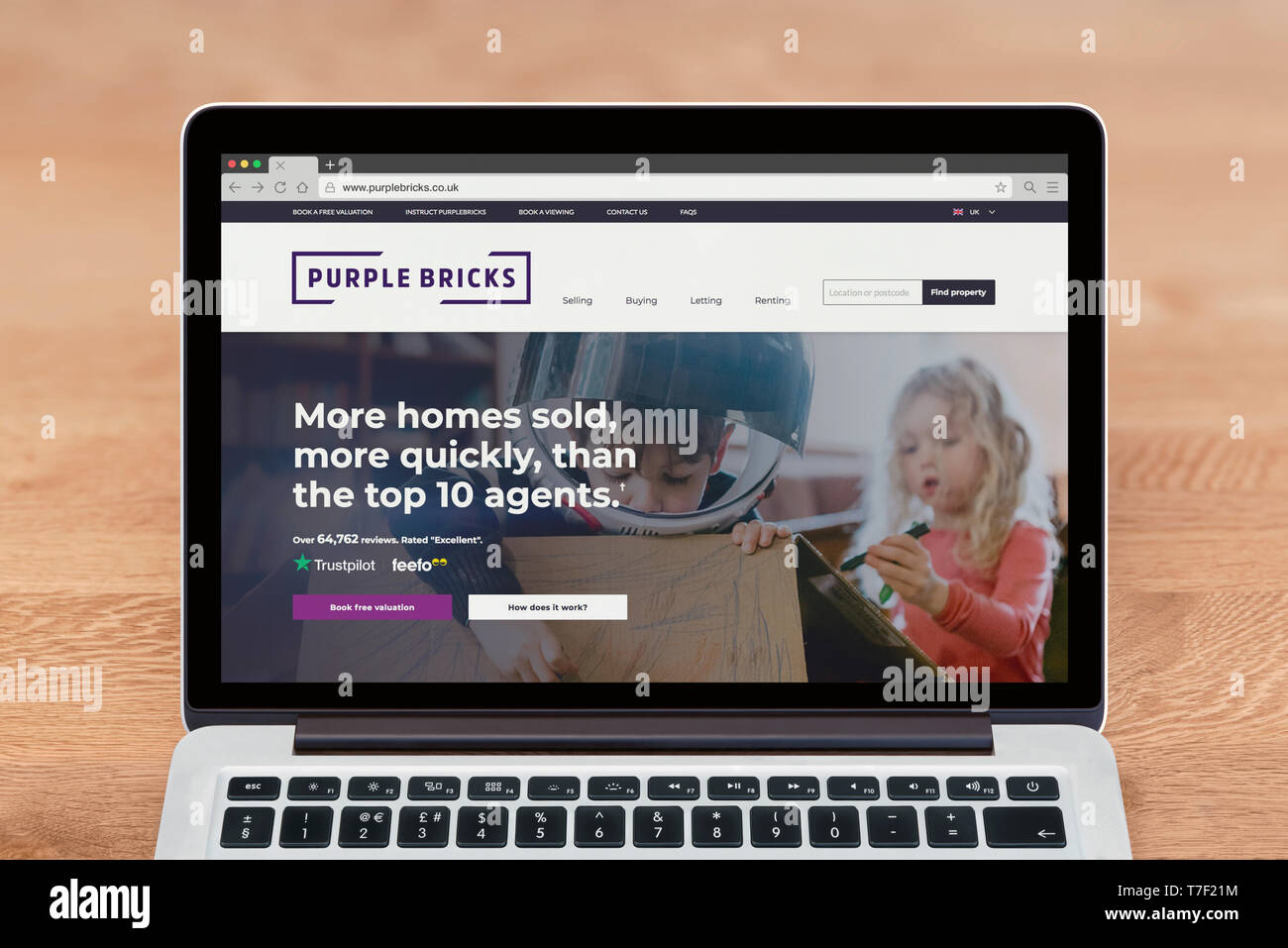 Un Macbook de Apple muestra el sitio web de ladrillos de color púrpura (uso Editorial solamente). Foto de stock