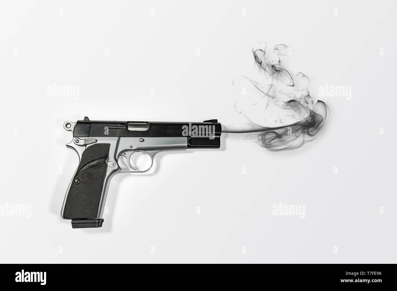 Un semi-automático 9mm pistola de fumar sobre fondo blanco brillante con un montón de espacio negativo para copiar. Foto de stock