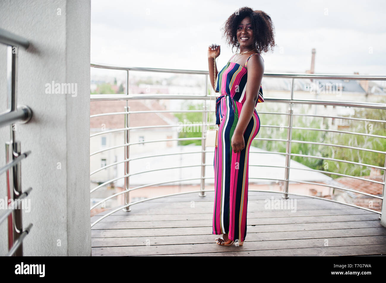 Moda Mujer afroamericana mono rayas en rosa con bolso planteados