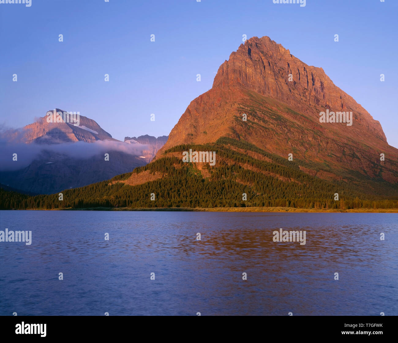 Estados Unidos, Montana, el Parque Nacional de Los Glaciares, la luz del amanecer en Grinnell Point (centro) y el Monte Gould (extremo izquierdo) por encima del lago Swiftcurrent. Foto de stock