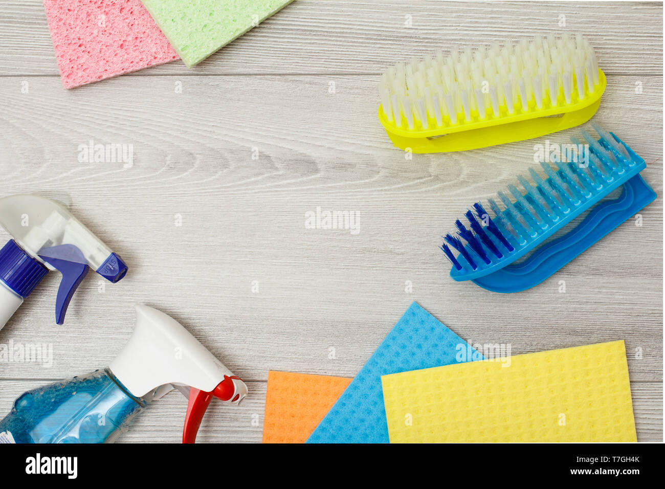 Botellas de detergente, color servilletas de microfibra sintético y el  cepillo para la limpieza de madera gris de fondo con copia espacio en el  centro. Conjunto de limpi Fotografía de stock -