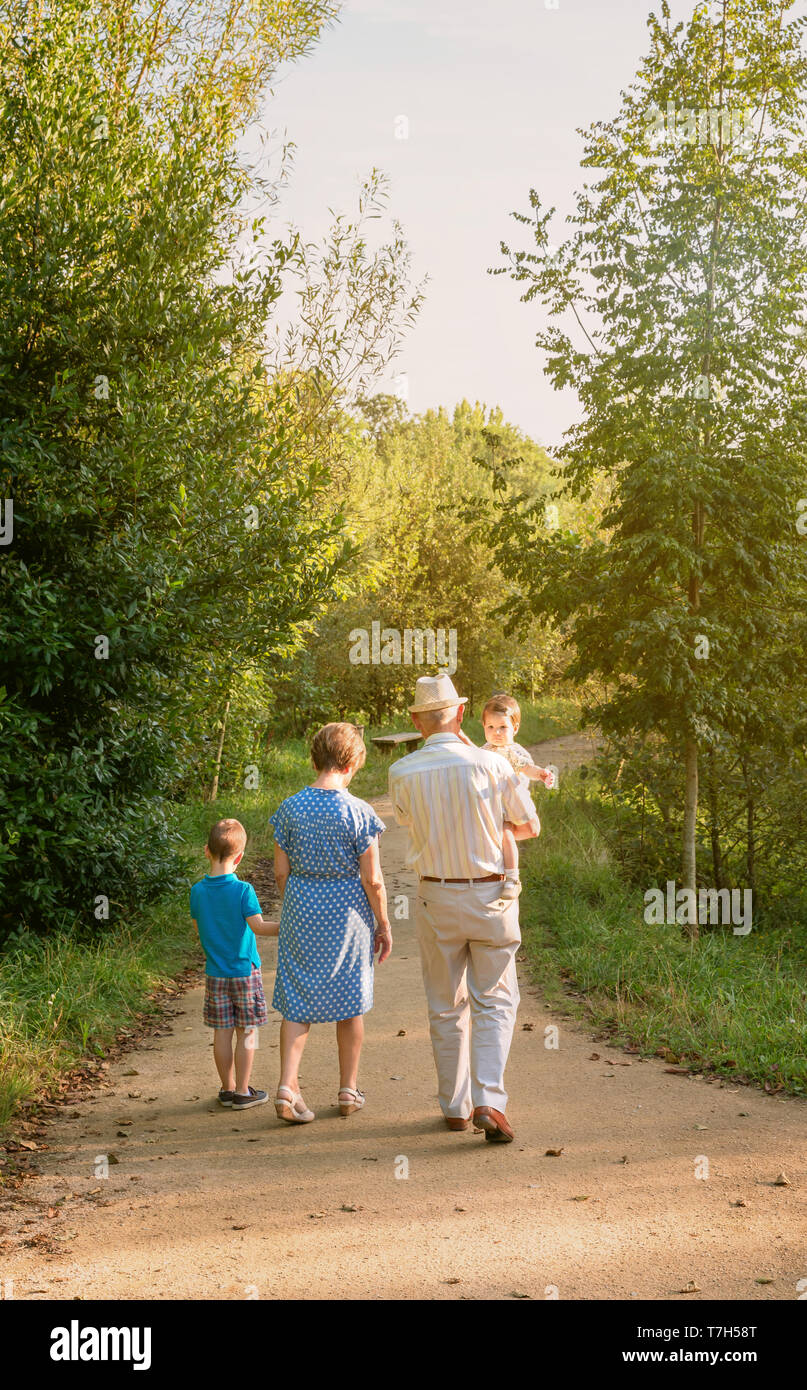 Vista posterior de abuelos y nietos caminando por un sendero de la naturaleza Foto de stock