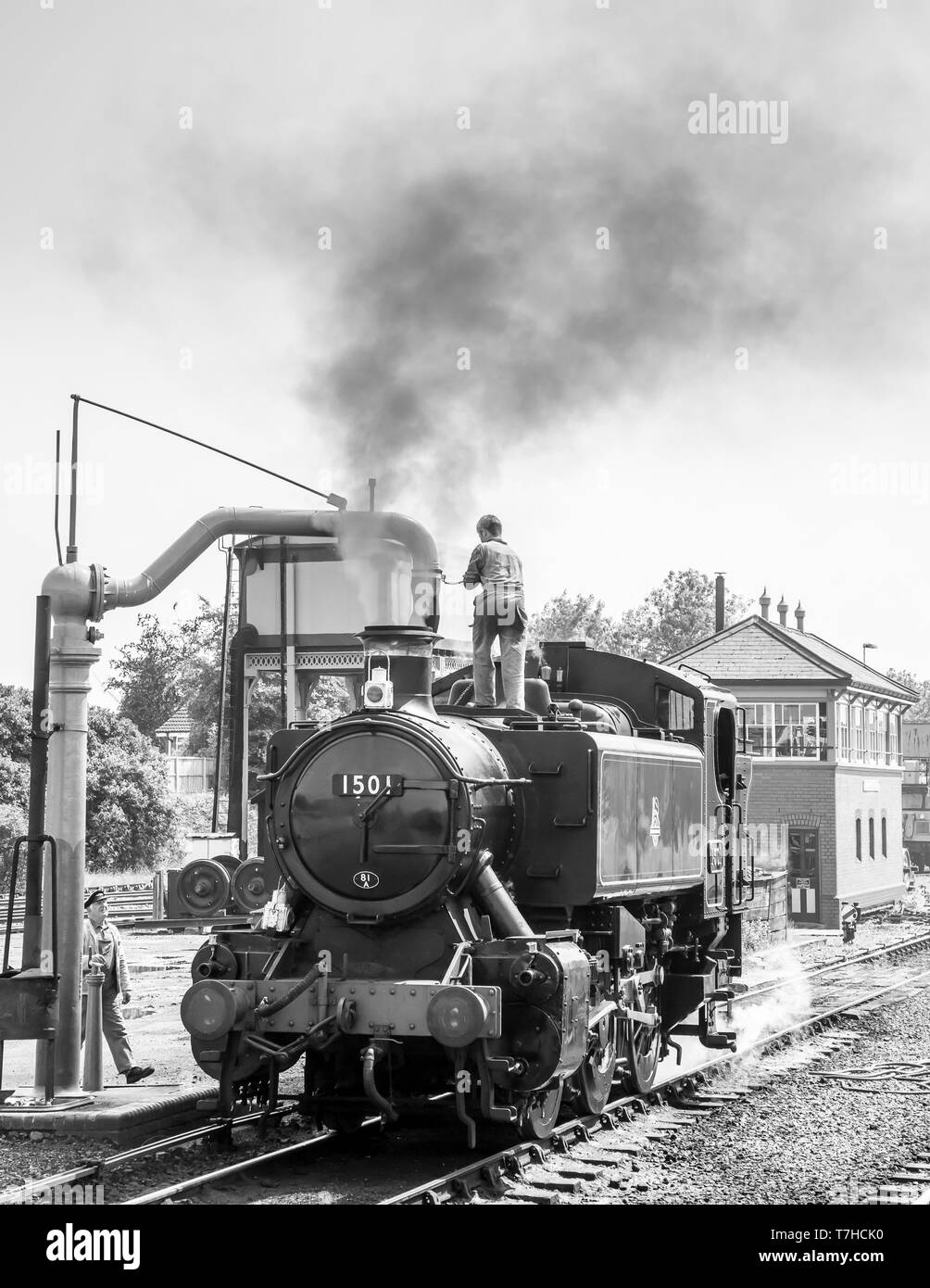 Locomotora de vapor monocroma vintage del Reino Unido en sidings en la estación de Severn Valley Railway Kidderminster tomando agua, tripulación de tren de vapor en una grúa de parada de agua. Foto de stock