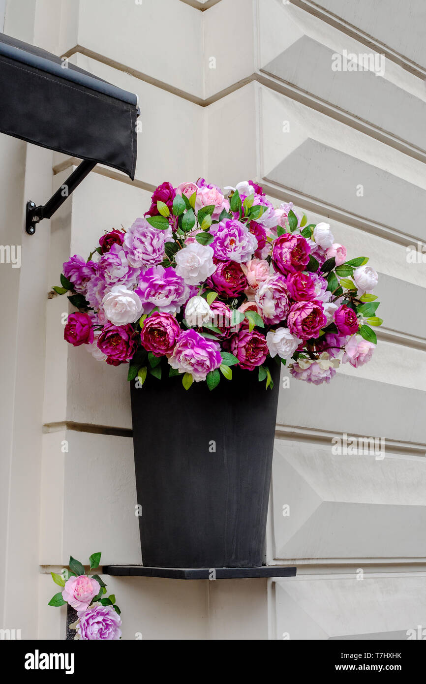 Artificial en peonía jarrón negro sobre la fachada de la casa. Paeony  colorido ramo de flores en la pared, composición floral Fotografía de stock  - Alamy
