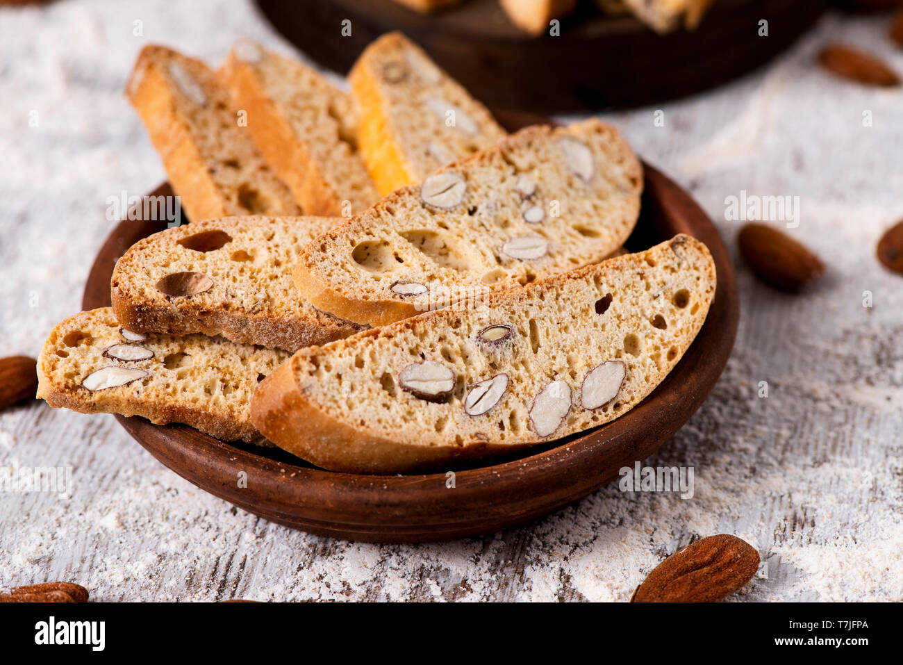 Primer plano de una placa de madera con unos carquinyolis, pasteles típicos de Cataluña, España, elaborado con almendras, sobre una tabla de madera rústica gris Foto de stock