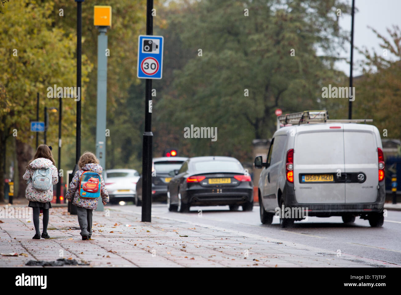 Los niños caminando a la escuela junto a una carretera congestionada en Wandsworth, Londres Foto de stock