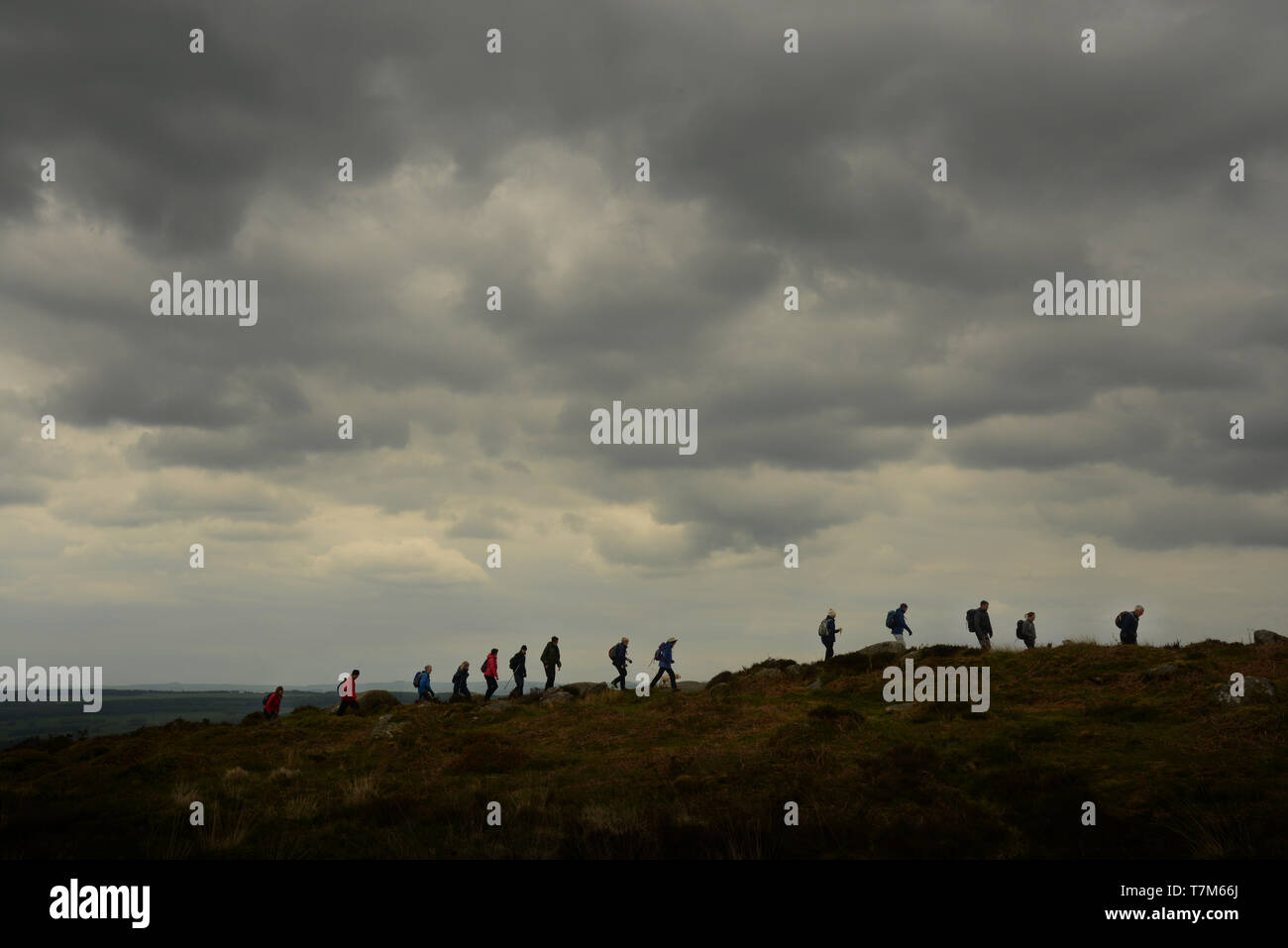 Caminantes mitad perfilados contra el horizonte siga en línea a lo largo de Curbar Edge, Esperanza Valle, Derbyshire, Inglaterra. Foto de stock