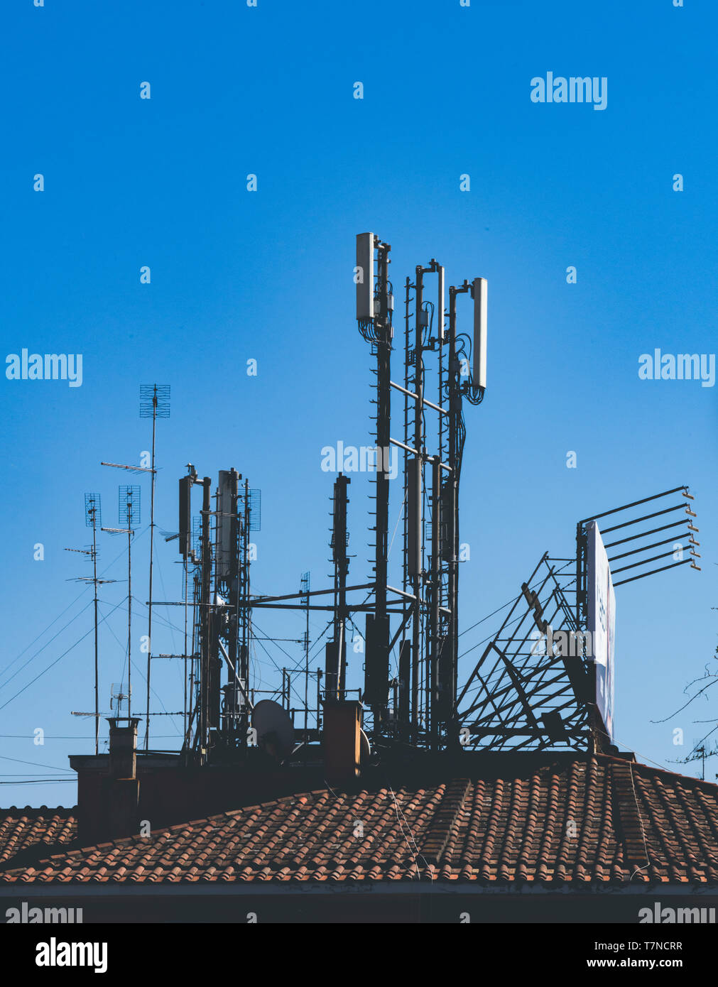 Plano amplio de diferentes antenas antena para la radio y la televisión y la transmisión móvil de teja edificio contra el cielo azul Foto de stock