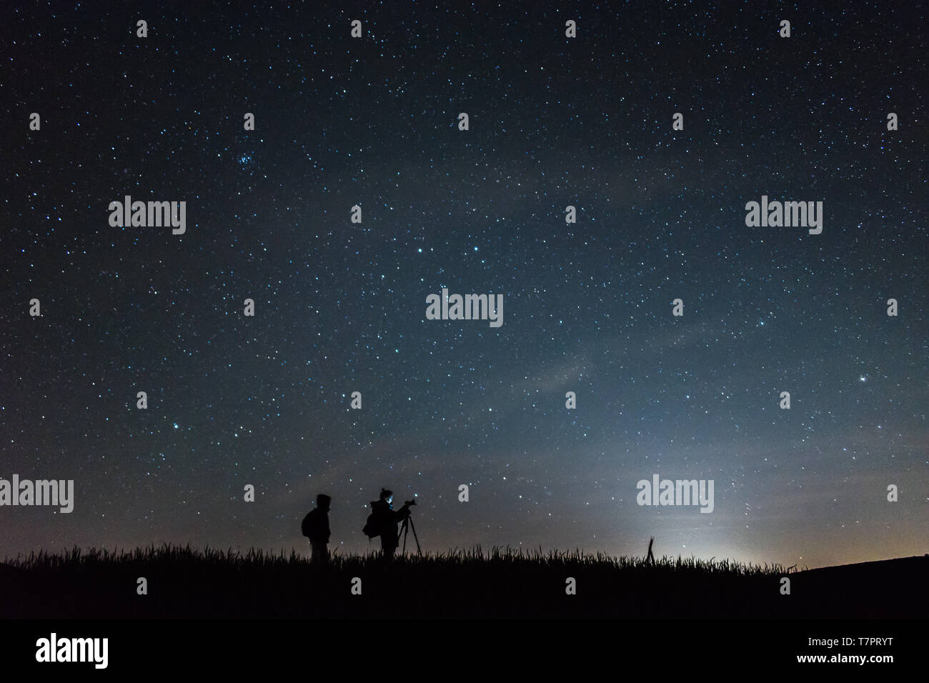 Fotógrafos de silueta con un cielo lleno de estrellas en la noche de fondo Foto de stock