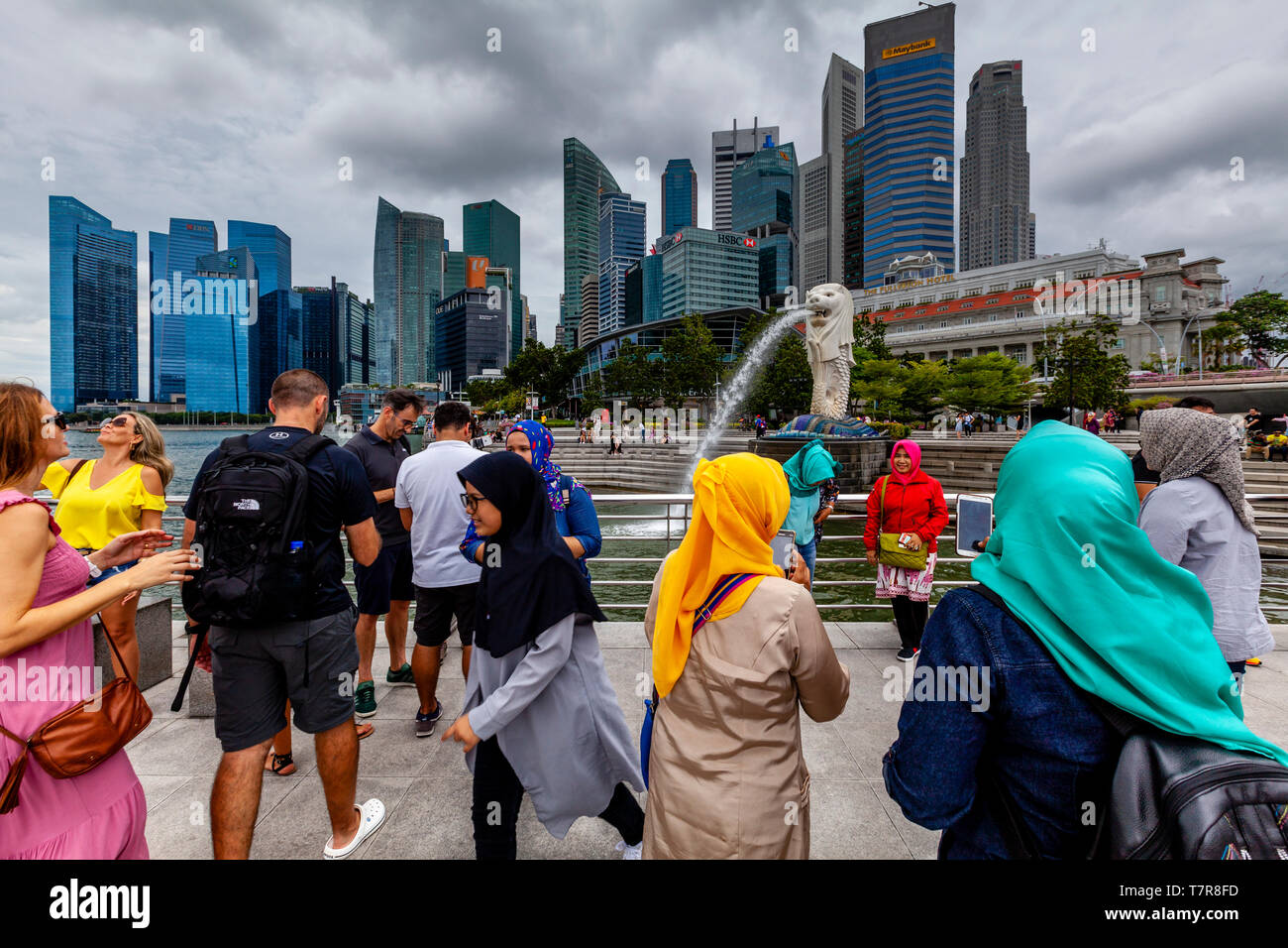 Los turistas posando para fotos delante de la estatua Merlion y horizonte de Singapur, Singapur, Sudeste de Asia Foto de stock