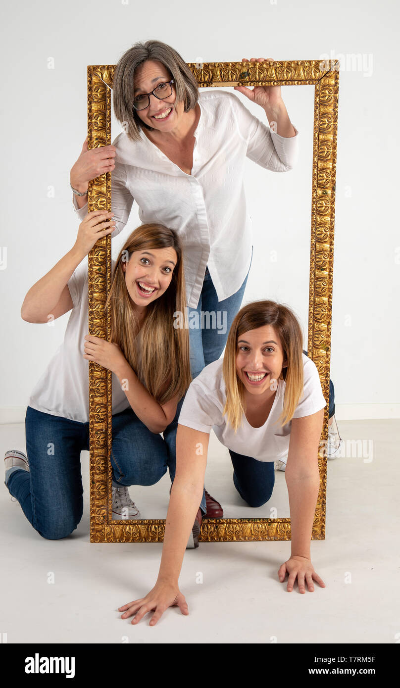 Familia compuesta por la madre y dos hermanas gemelas plantean dentro de un  marco Pictórico en un estudio fotográfico y en una actitud muy divertida  Fotografía de stock - Alamy