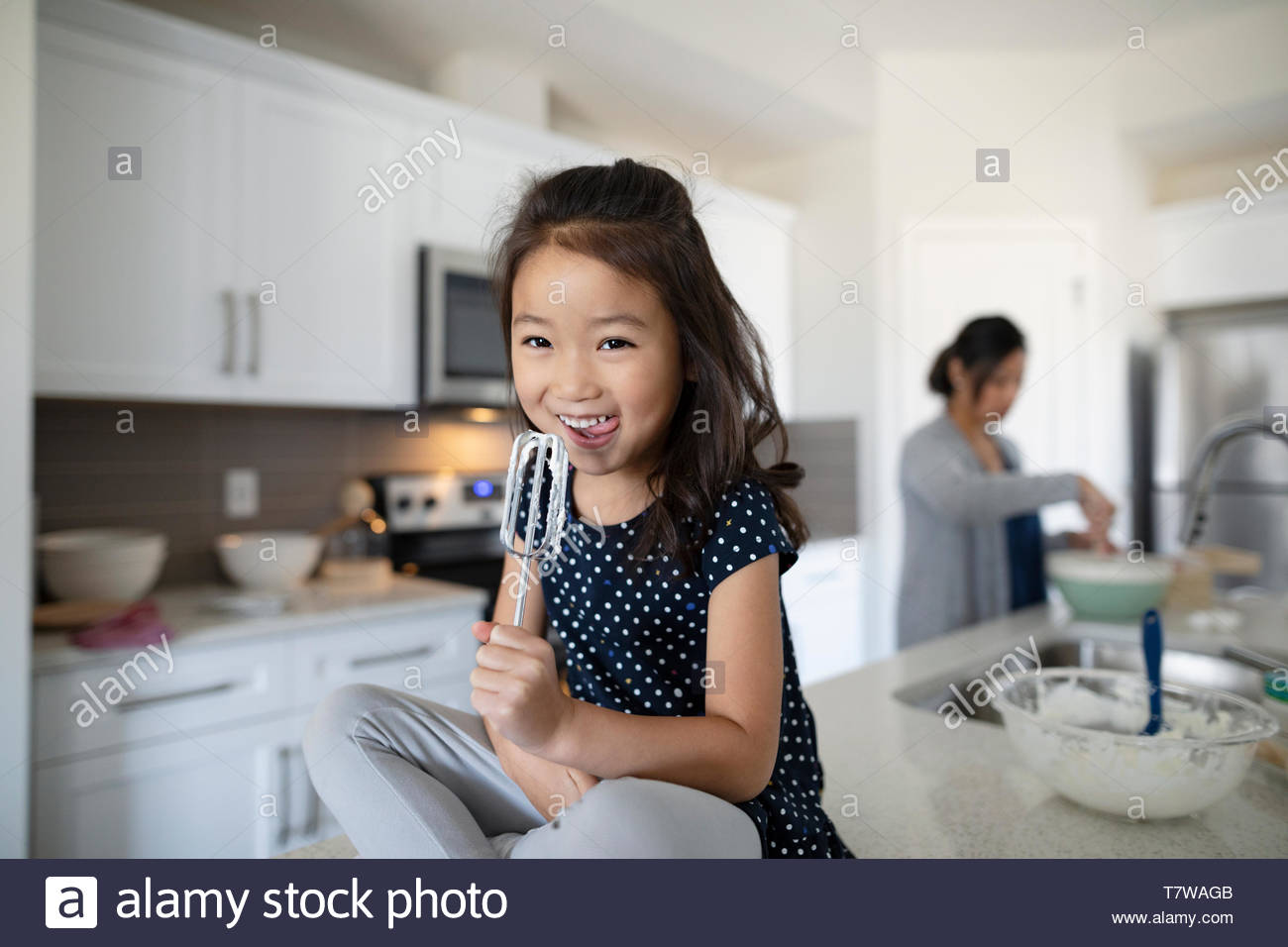 Retrato niña lindo lamiendo glaseado del batidor en la cocina Foto de stock