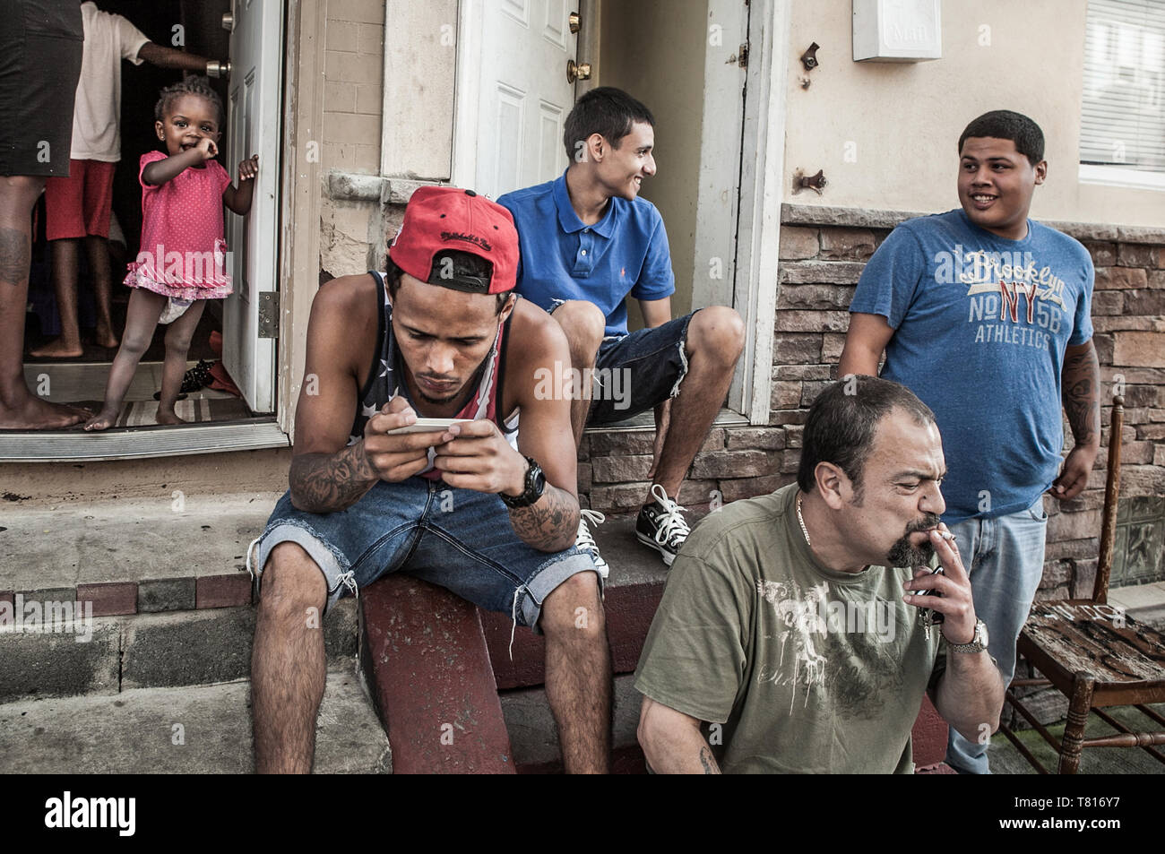 Los amigos y la familia sentarse fuera de casa en una fila en el norte de Philadelpia Kennsington Foto de stock