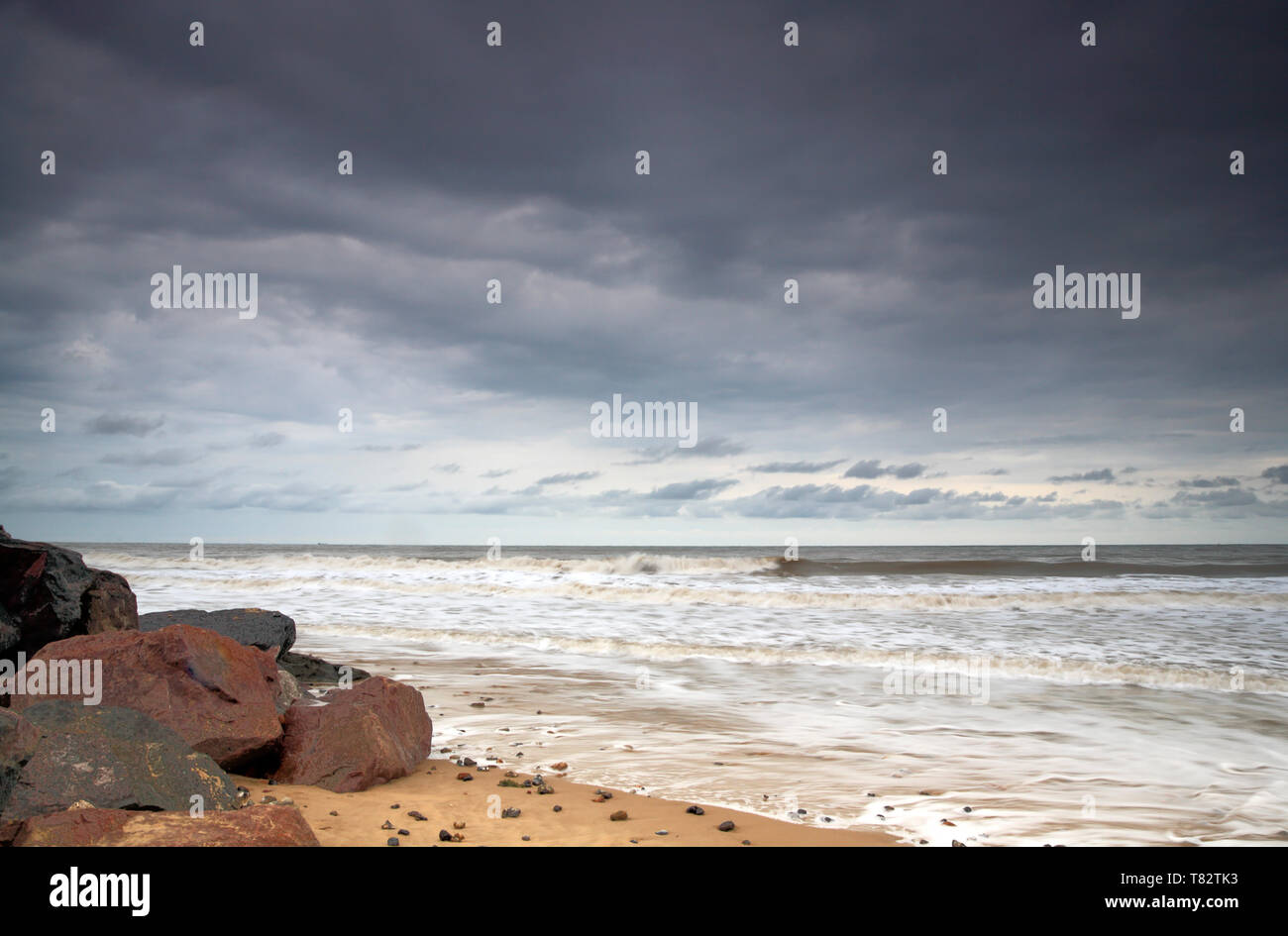 Una vista de la arena, el mar y el cielo, con la rotura de las nubes, en la costa de Norfolk en Happisburgh, Norfolk, Inglaterra, Reino Unido, Europa. Foto de stock