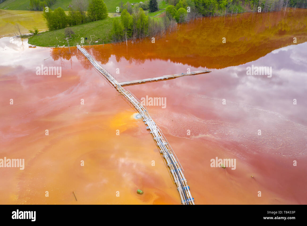 Vista aérea de drenaje ácido de mina, mina de cobre rojo colorido agua inundando el entorno natural por zumbido. Geamana, Rosia Montana, Rumania Foto de stock