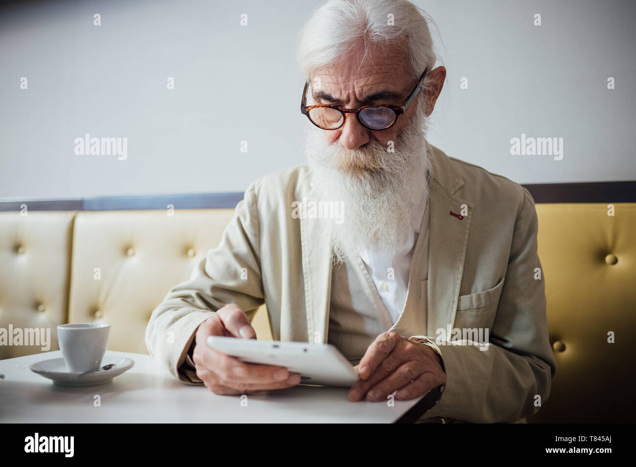 Empresario Senior utilizando digital comprimido en cafe Foto de stock