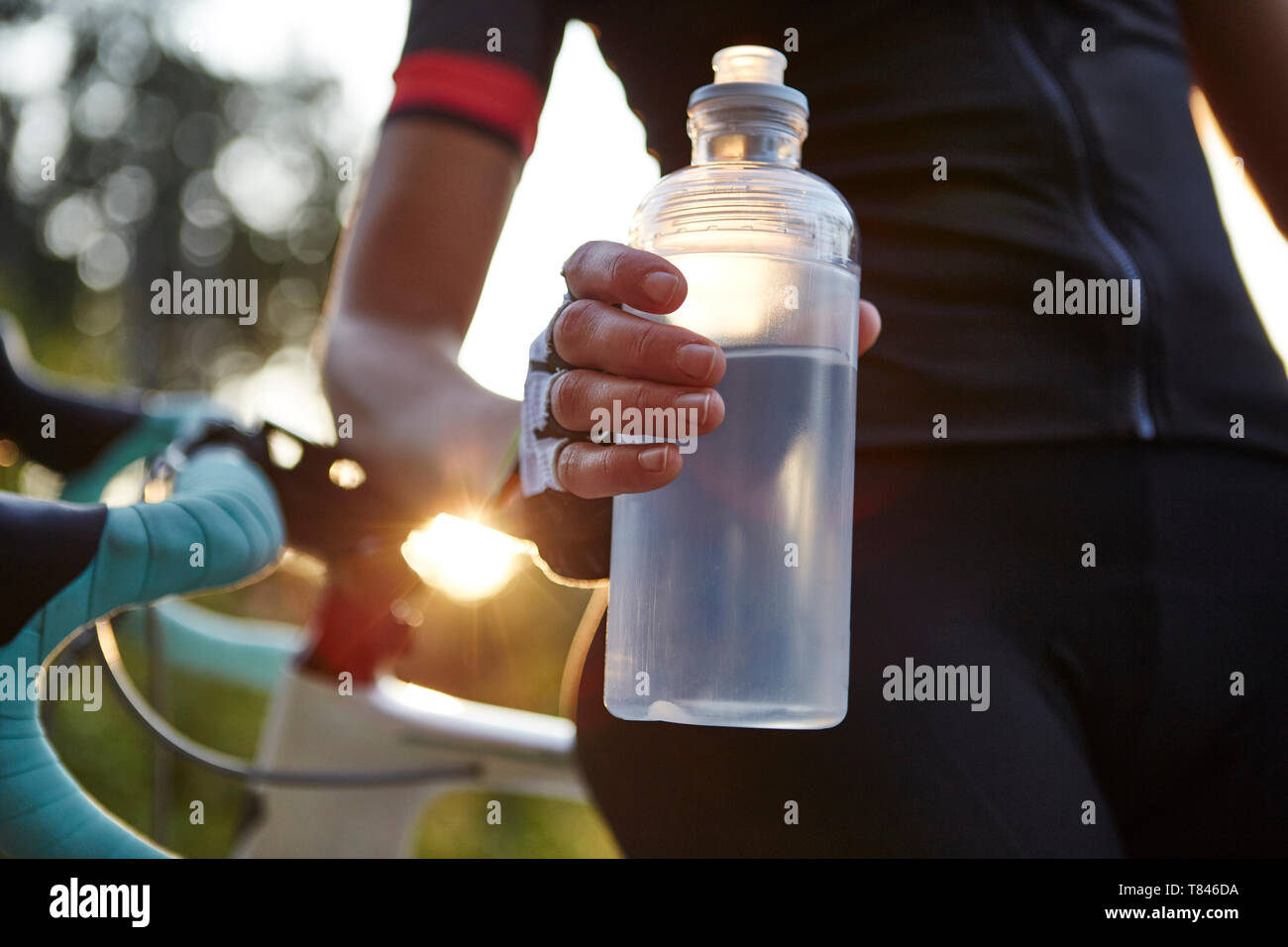 Ciclista femenina sosteniendo la botella de agua, sección intermedia Foto de stock
