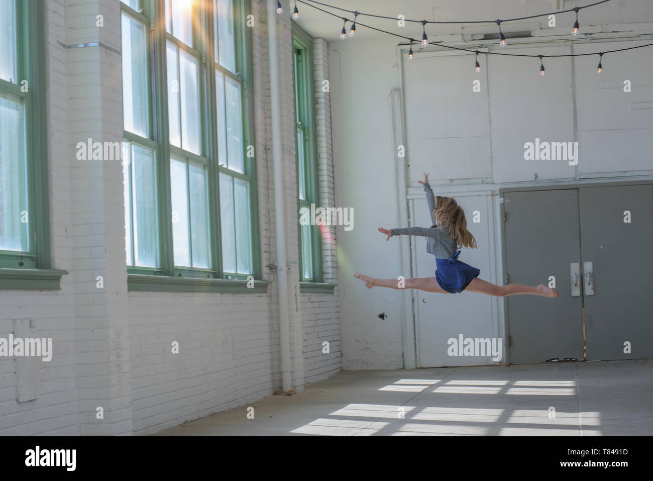 Adolescente con cabello marrón largo saltando en medio del aire dance studio Foto de stock