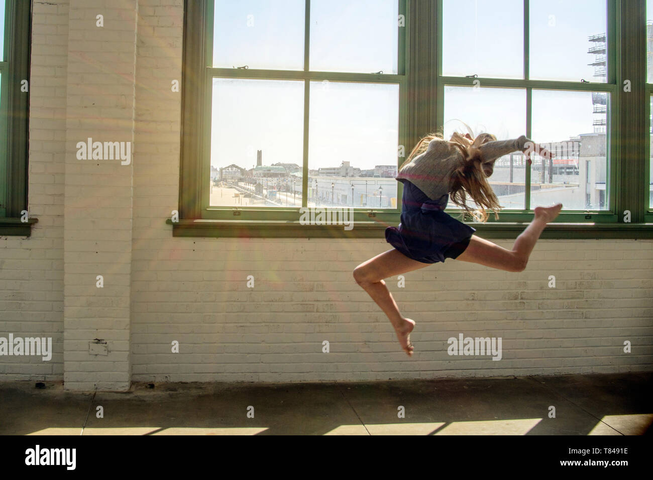 Adolescente con cabello marrón largo saltando en medio del aire dance studio Foto de stock