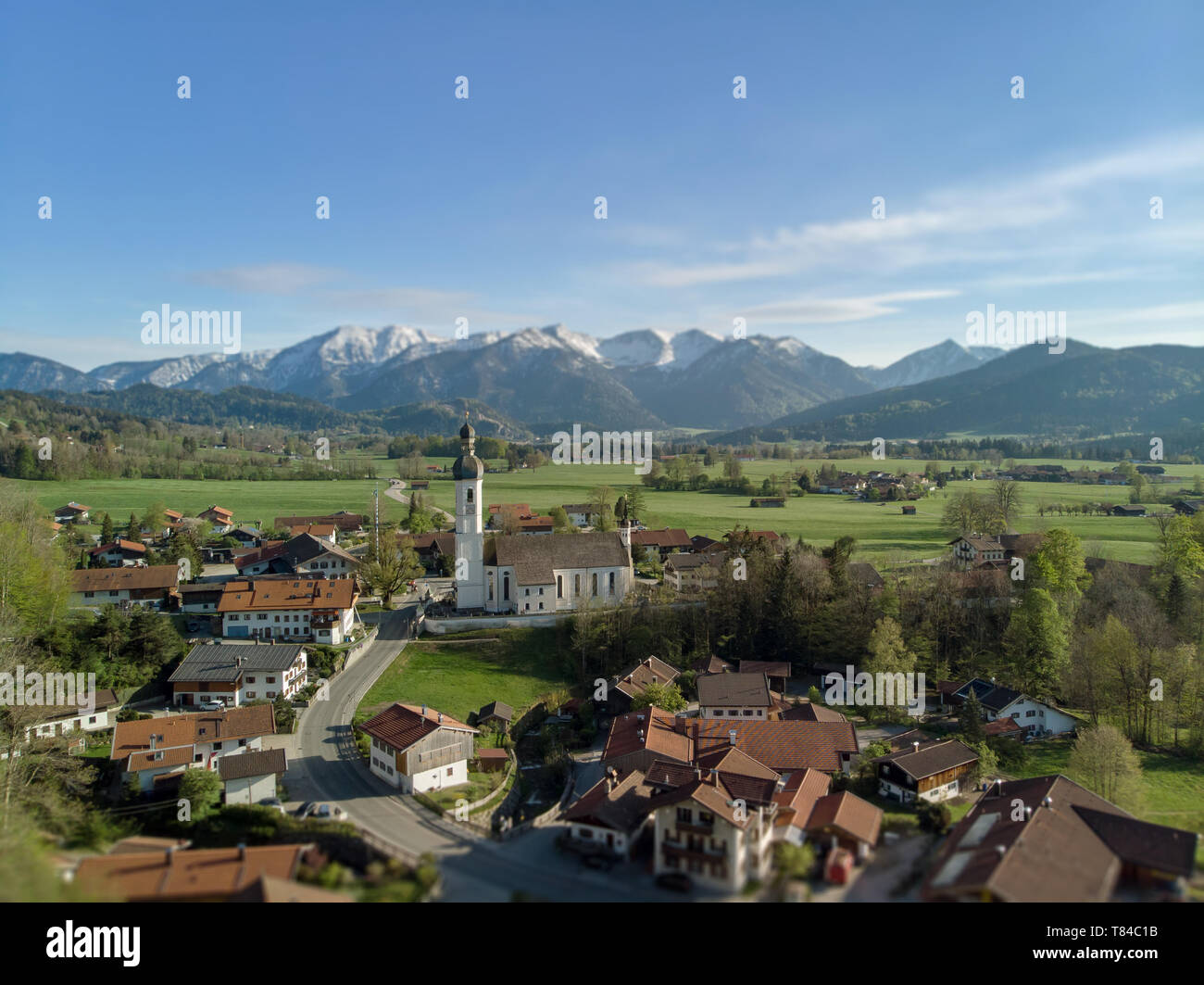 Auténtico pueblo bávaro en medio de bellos paisajes de los alpes con claros en el fondo y un cielo azul Foto de stock