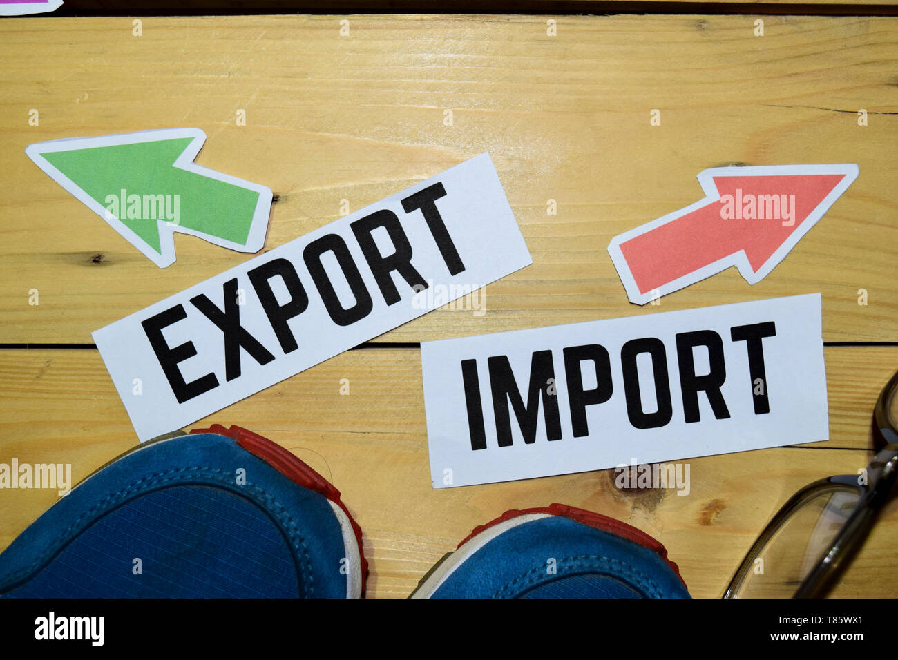 La importación o exportación de sentido opuesto signos con zapatillas de  deporte y gafas vintage de madera en el fondo. Los negocios, la educación y  las finanzas conceptos Fotografía de stock -