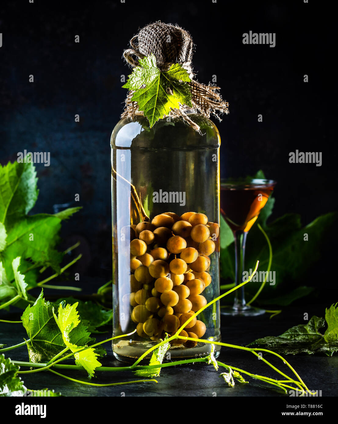 El brandy de uva tradicional chileno con todo el racimo de uvas dentro de  la botella. Aguardiente de uva una botella de brandy aguardiente de uva y  hojas de uva Fotografía de