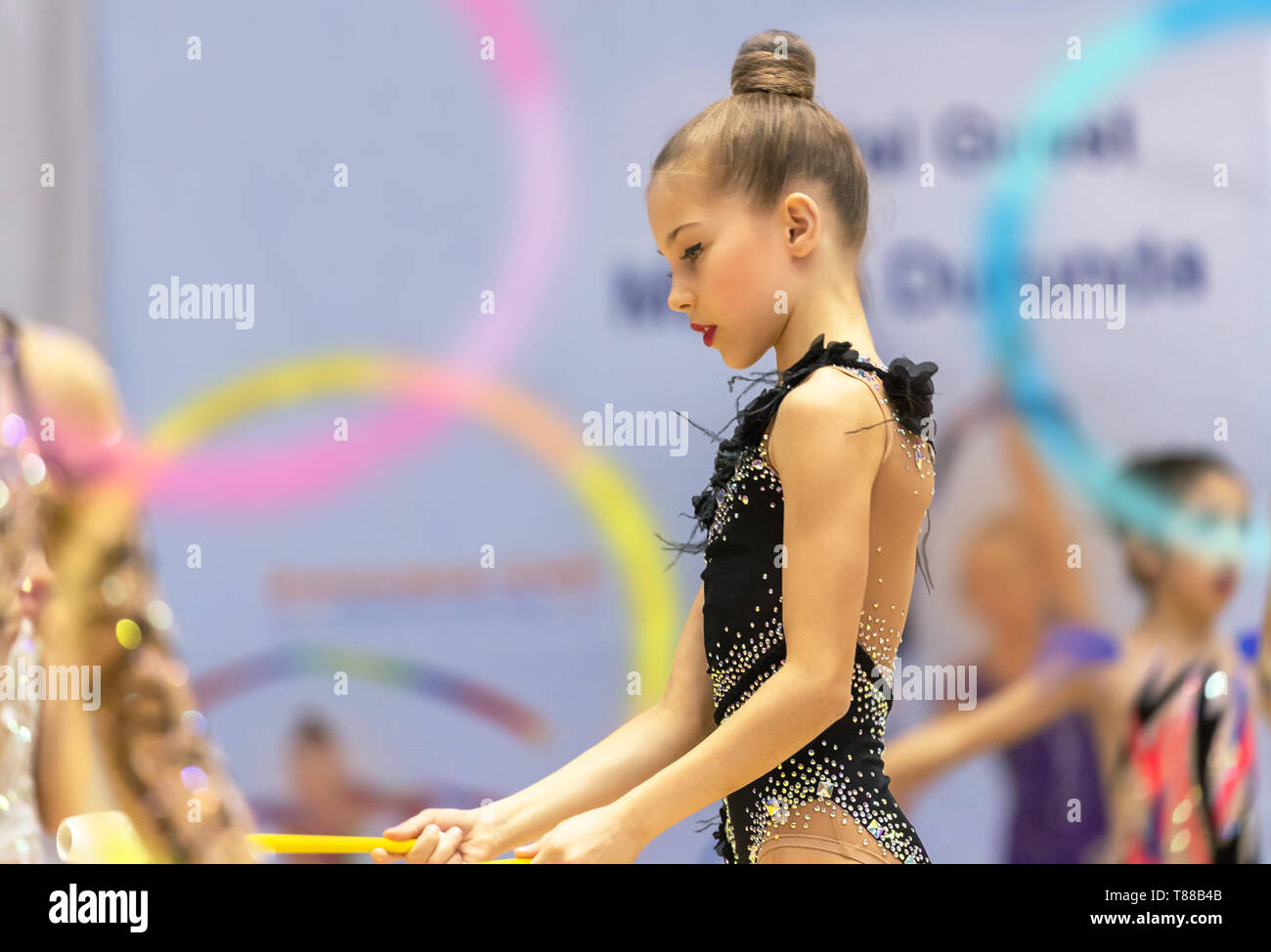 Bonita gimnasta en el concurso vestido de negro magnifico leotard realiza movimientos acrobáticos con un aro, escuela de gimnasia rítmica Fotografía de stock - Alamy Bonita gimnasta en el concurso vestido de negro magnifico leotard realiza movimientos acrobáticos con un aro, escuela de gimnasia rítmica Fotografía de stock - Alamy